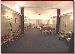 A quiet banquet hall with rows of chairs, round tables, and warm wall sconces
