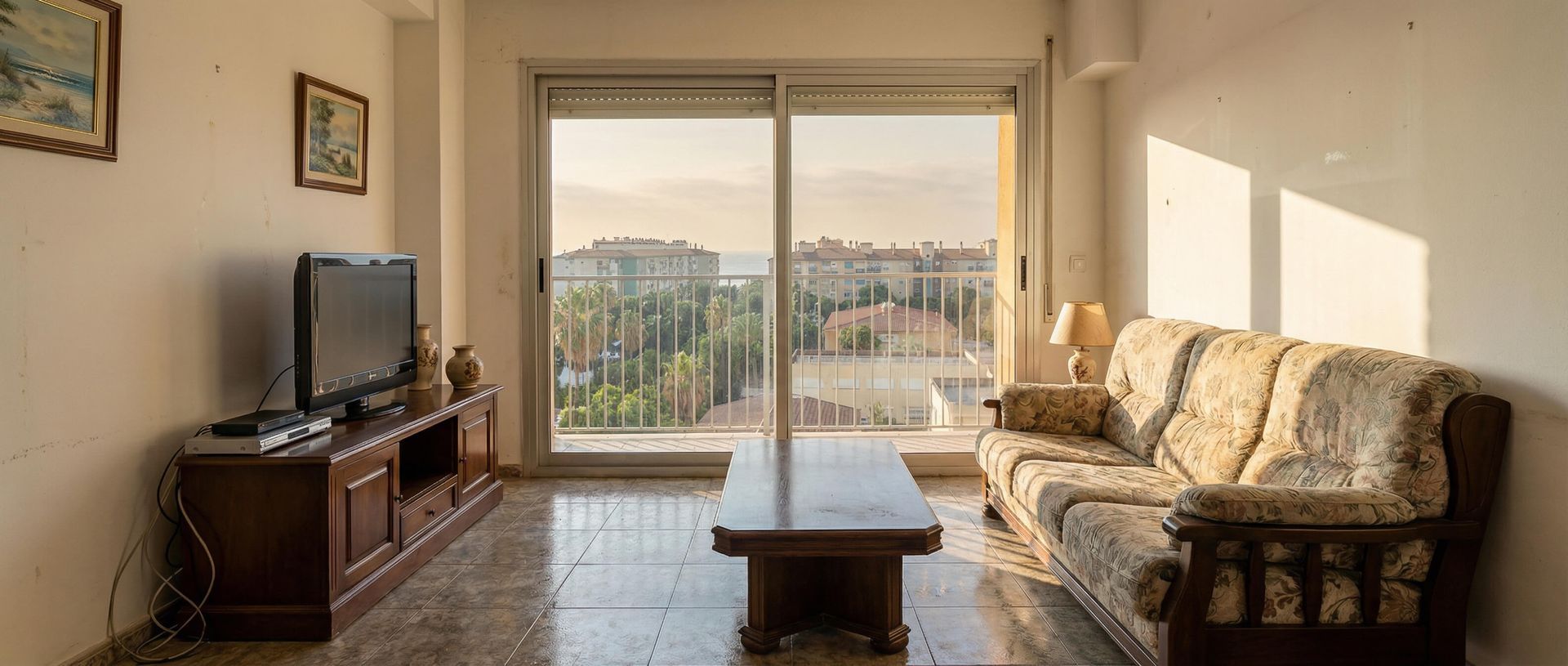 Luminoso salón con sofá, televisor, mesa de centro y grandes ventanales con vistas a la ciudad.