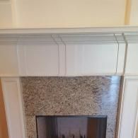 A white wood fireplace mantel surround with a speckled granite tile hearth.