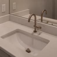 A modern white bathroom vanity with an undermount sink, brushed nickel faucet, and a wall mirror.