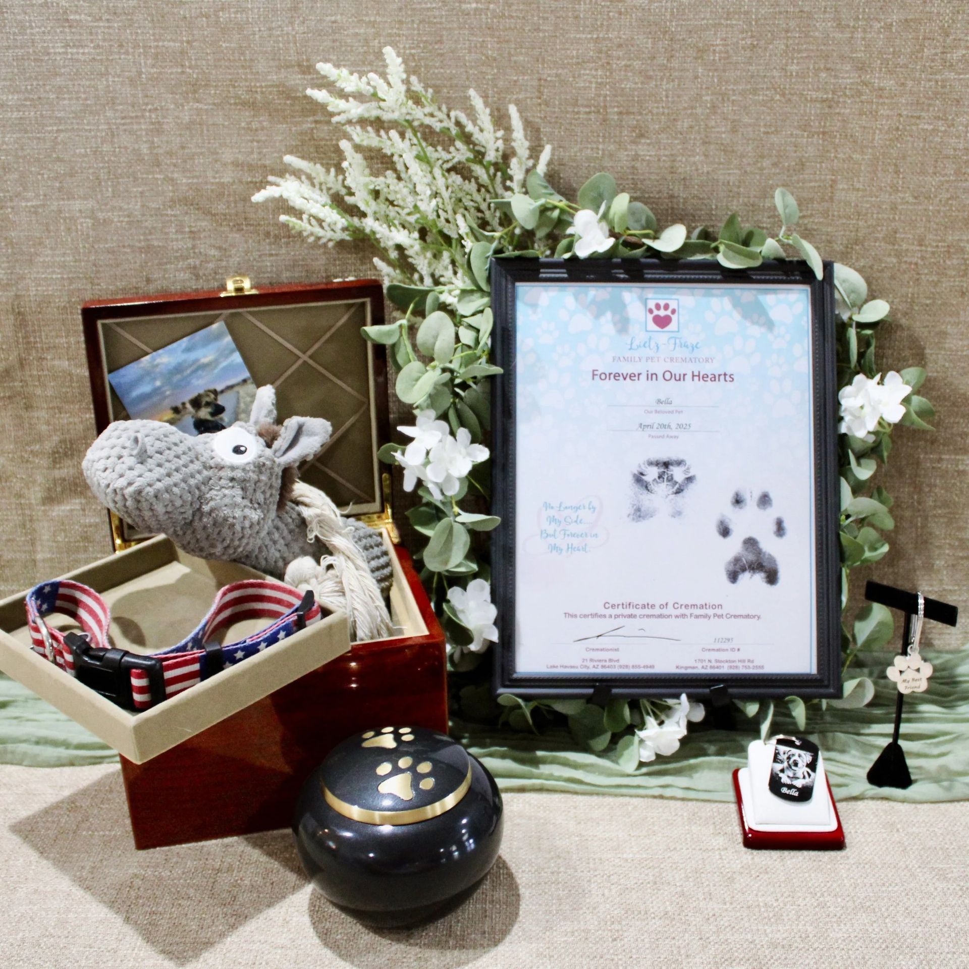 Pet memorial display with framed tribute, floral wreath, urn, and keepsakes on a tabletop