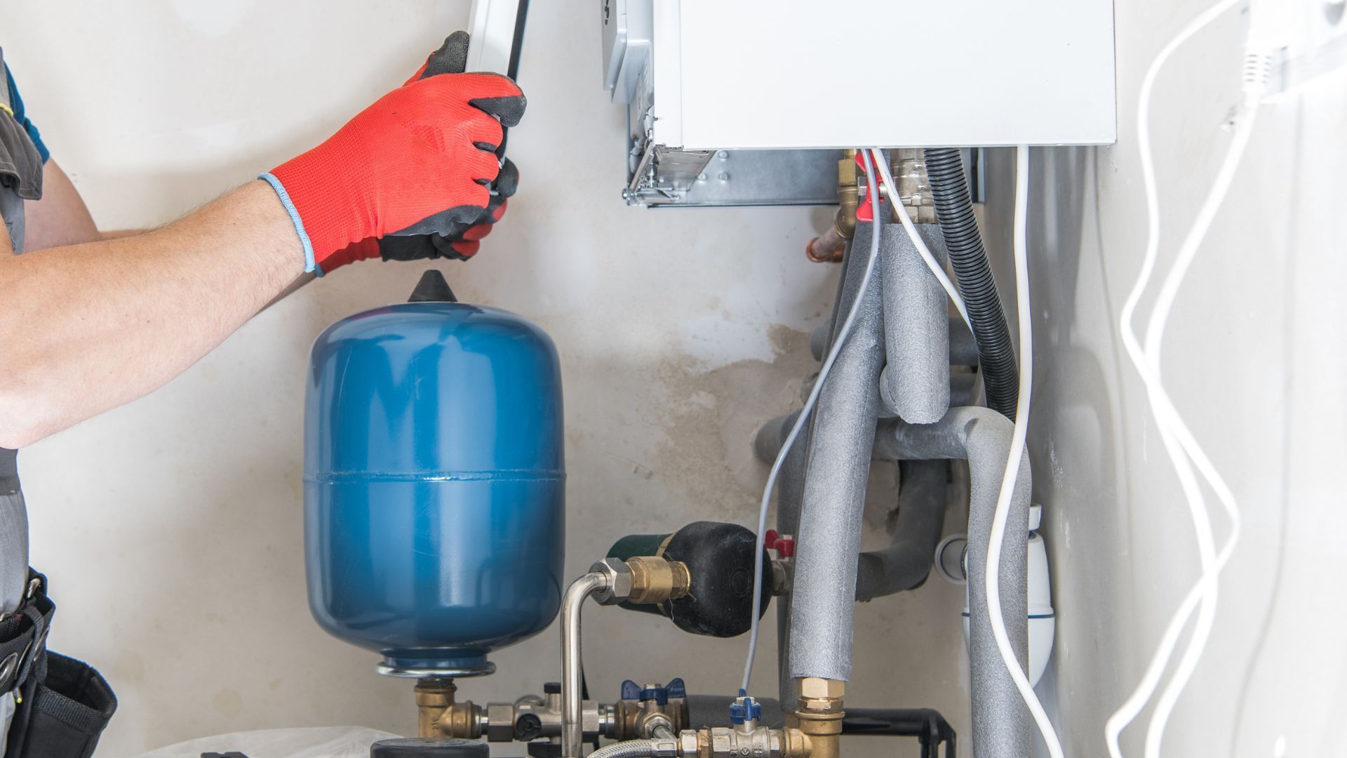 A man is working on a boiler in a room.