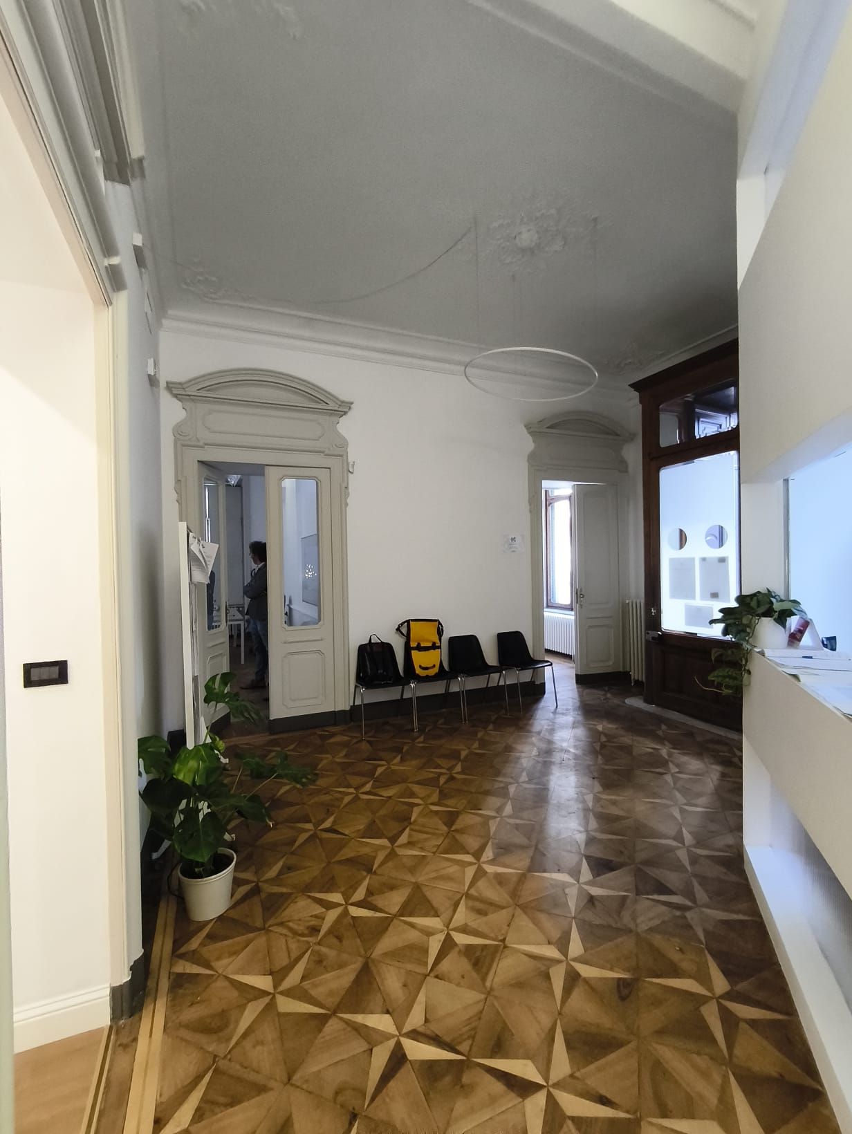 Corridoio con pavimento in legno decorato, pareti bianche e soffitti decorati.