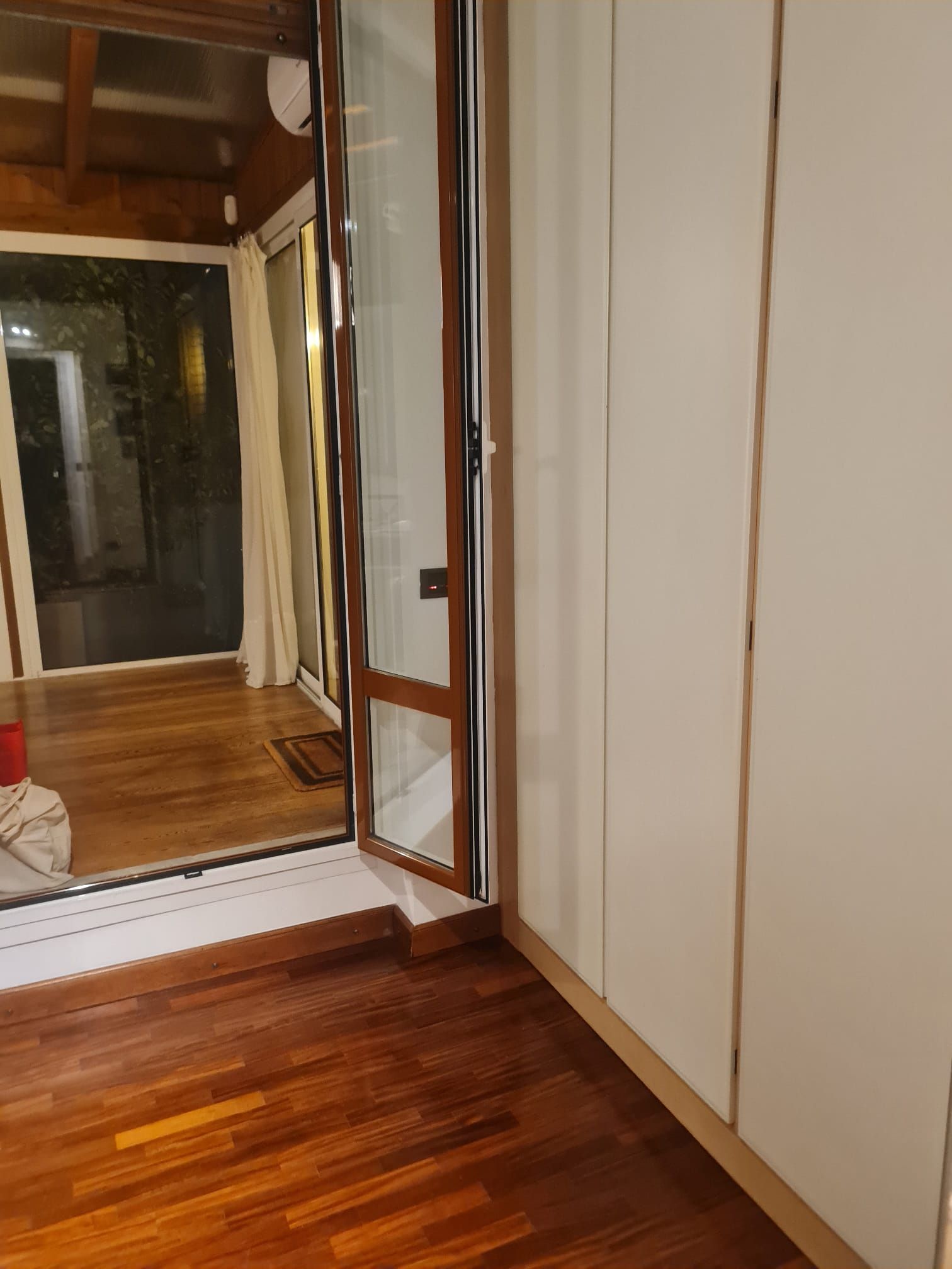 Pavimento in legno e porta con porticina per animali domestici, che si apre su una veranda.