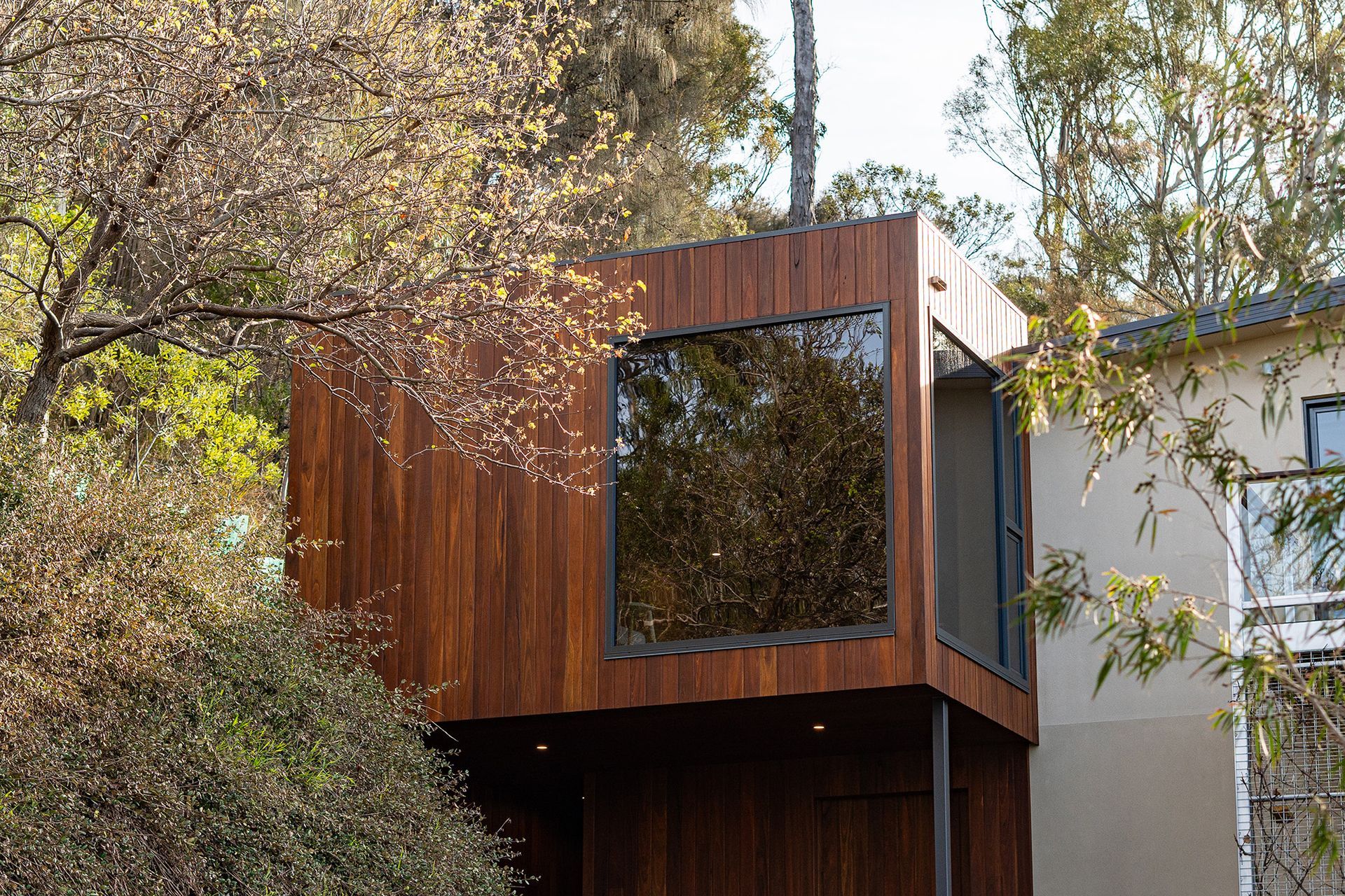 A wooden house with a lot of windows is surrounded by trees.