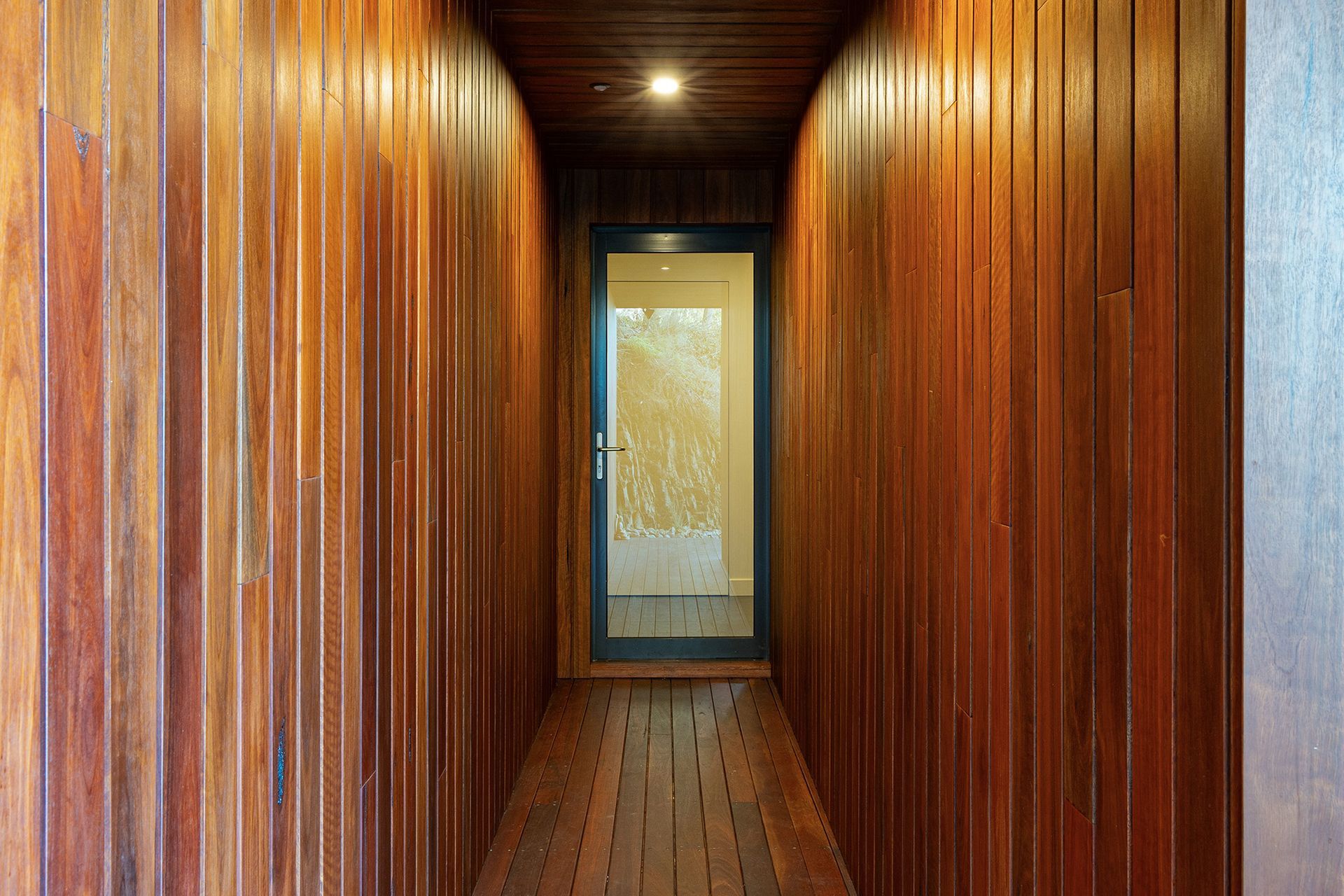 A long hallway with wood paneling and a glass door.