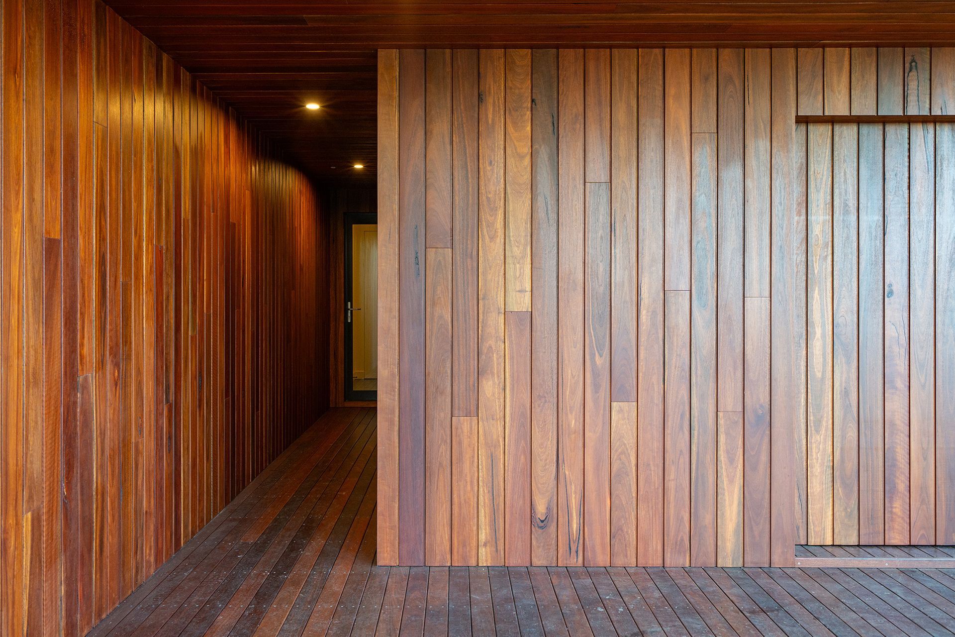 A hallway with wooden walls and floors in a house.