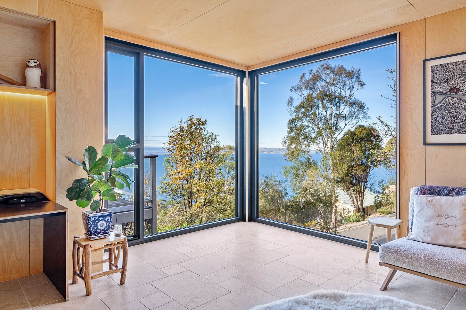 A living room with a lot of windows and a view of the ocean.