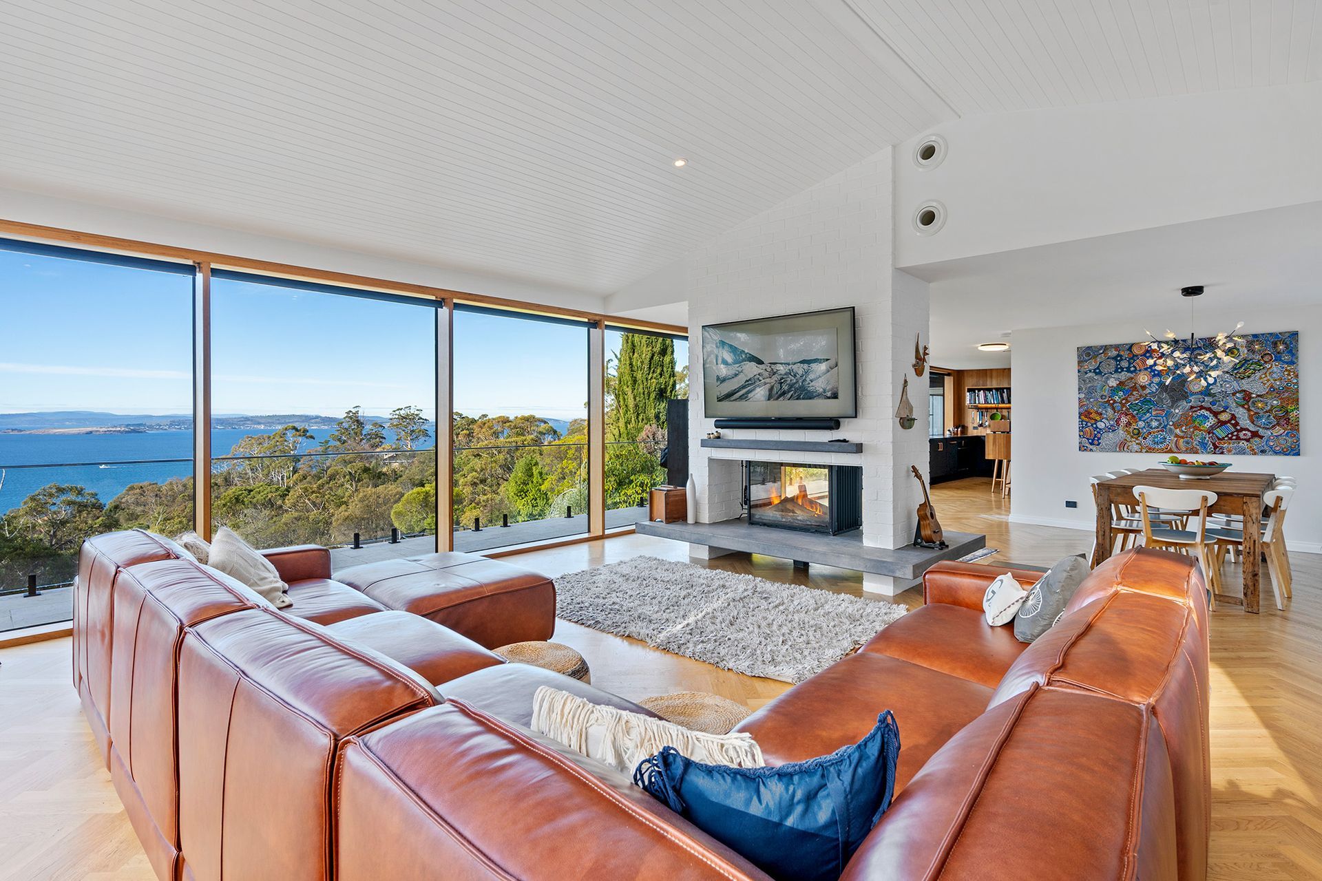 A living room with a couch and a fireplace with a view of the ocean.