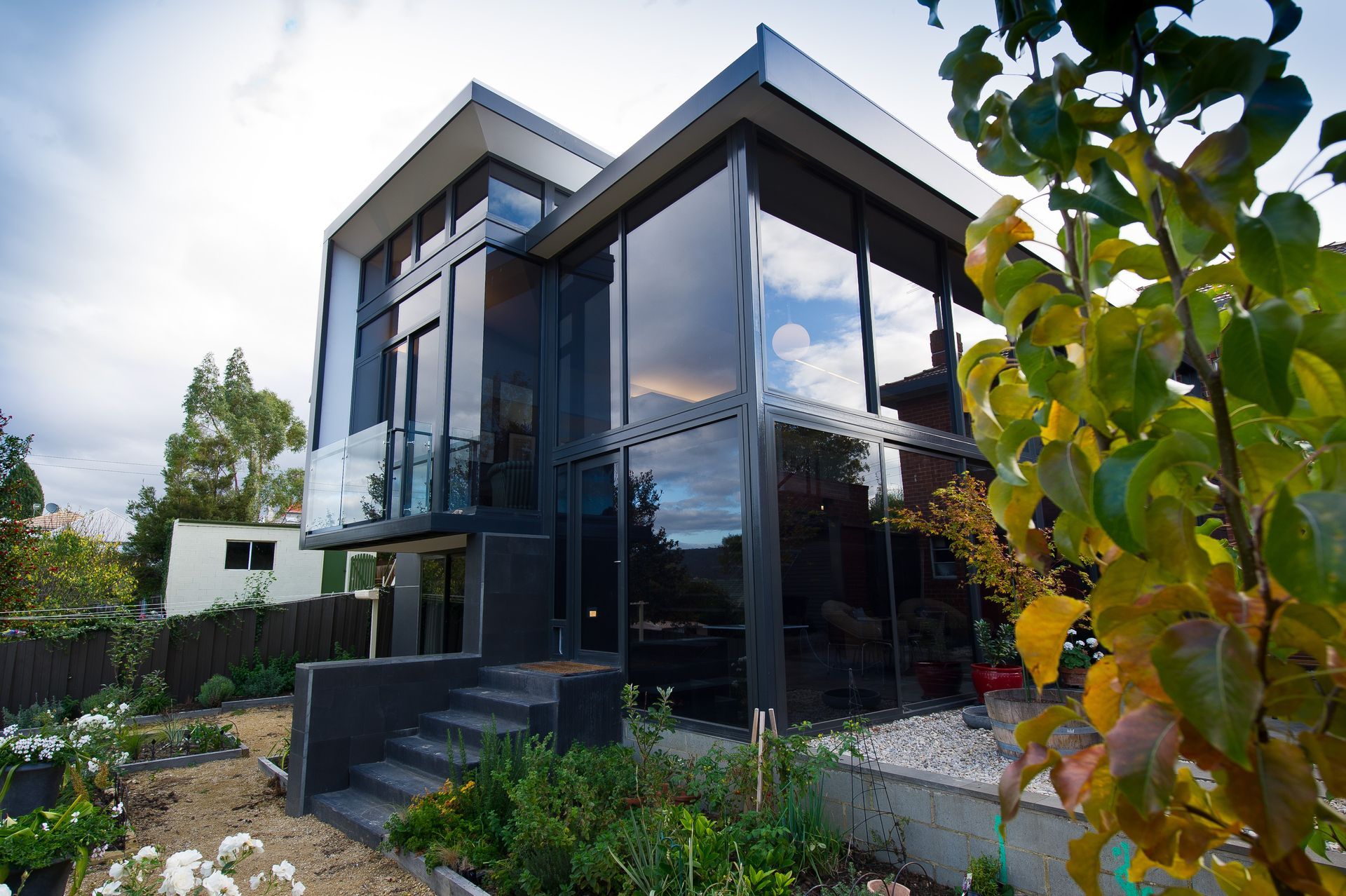 A large house with a lot of windows is surrounded by trees and bushes.