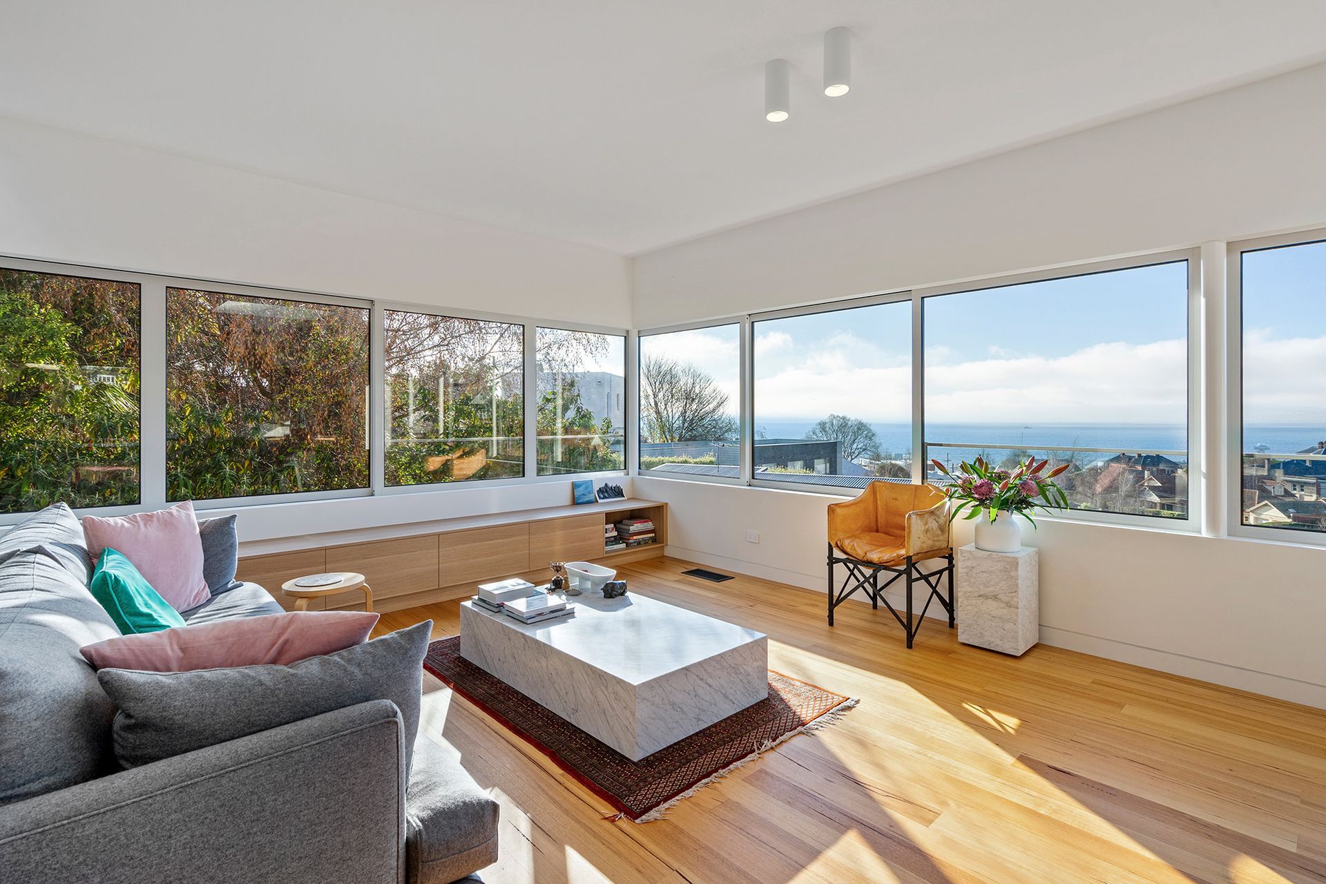 A living room with a lot of windows and a view of the ocean.