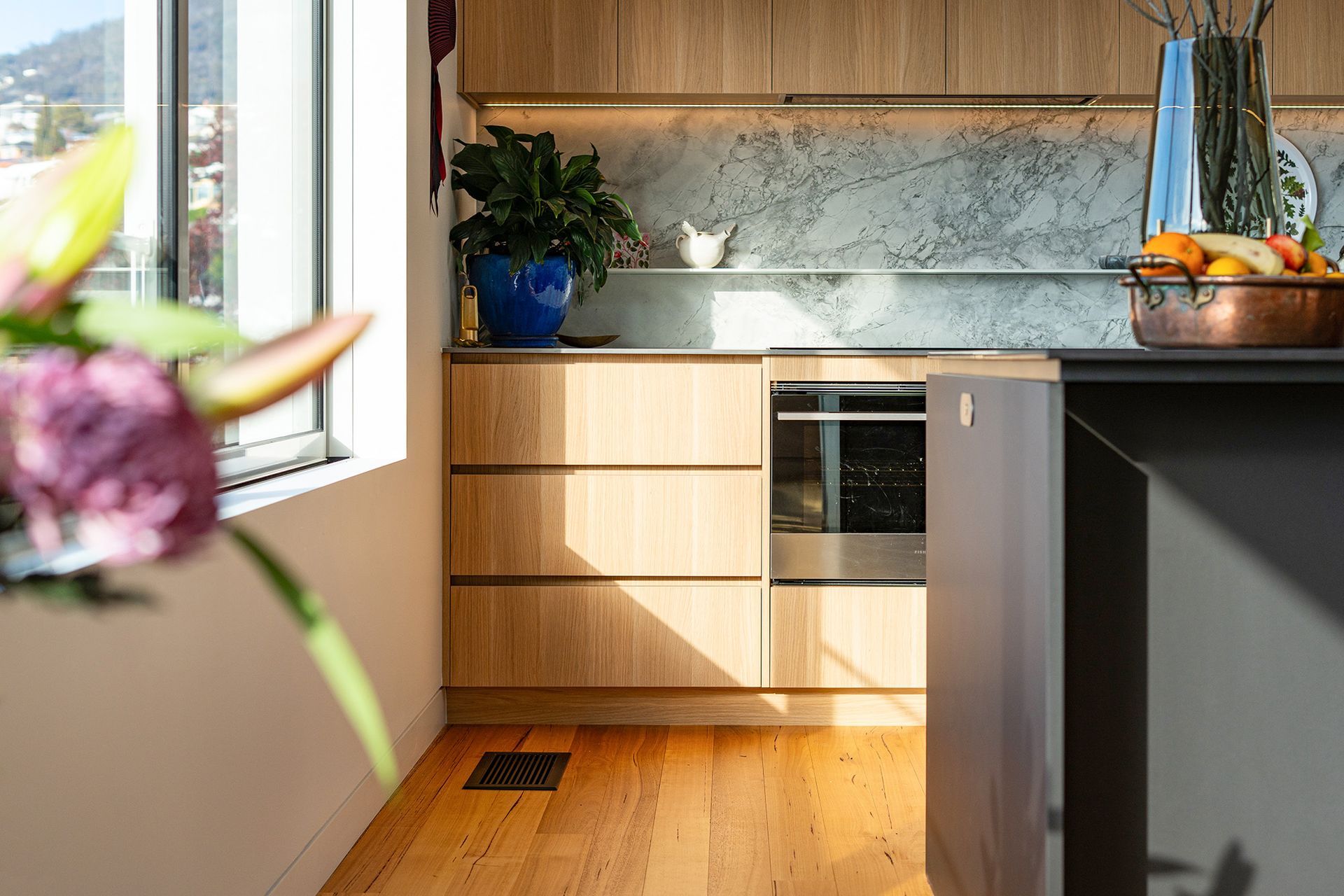 A kitchen with wooden cabinets , stainless steel appliances , and a vase of flowers on the counter.