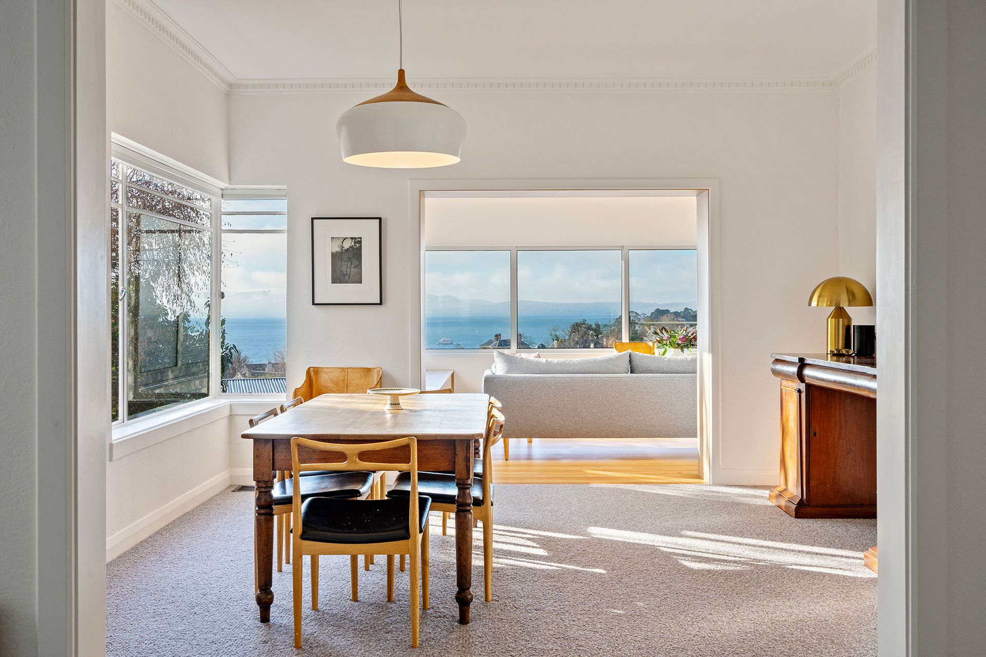 A dining room with a table and chairs and a view of the ocean.