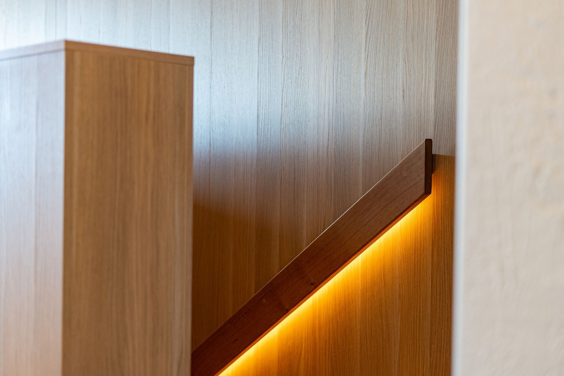 A wooden staircase with a light on the railing.