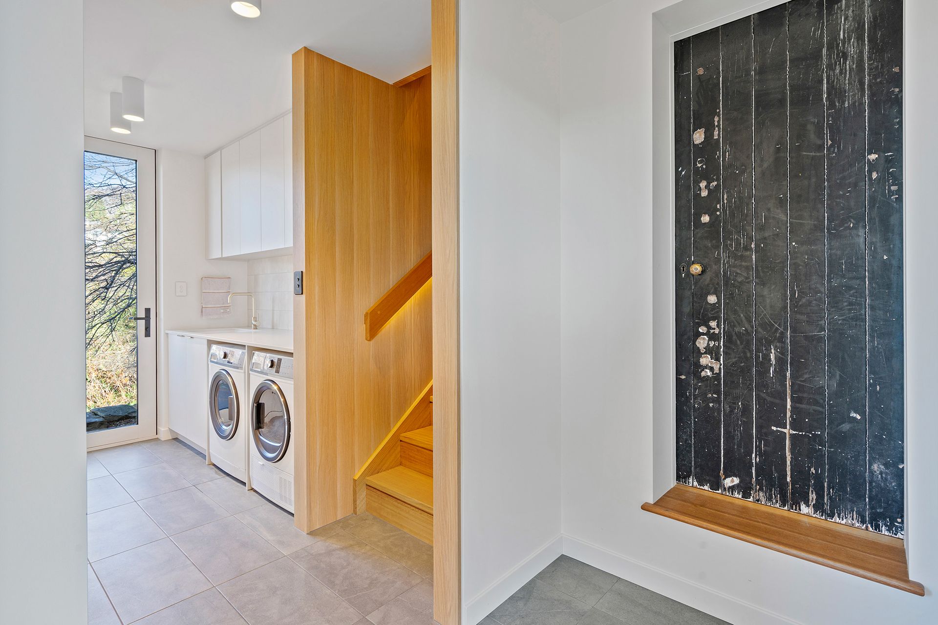 A laundry room with a washer and dryer and stairs leading up to the second floor.