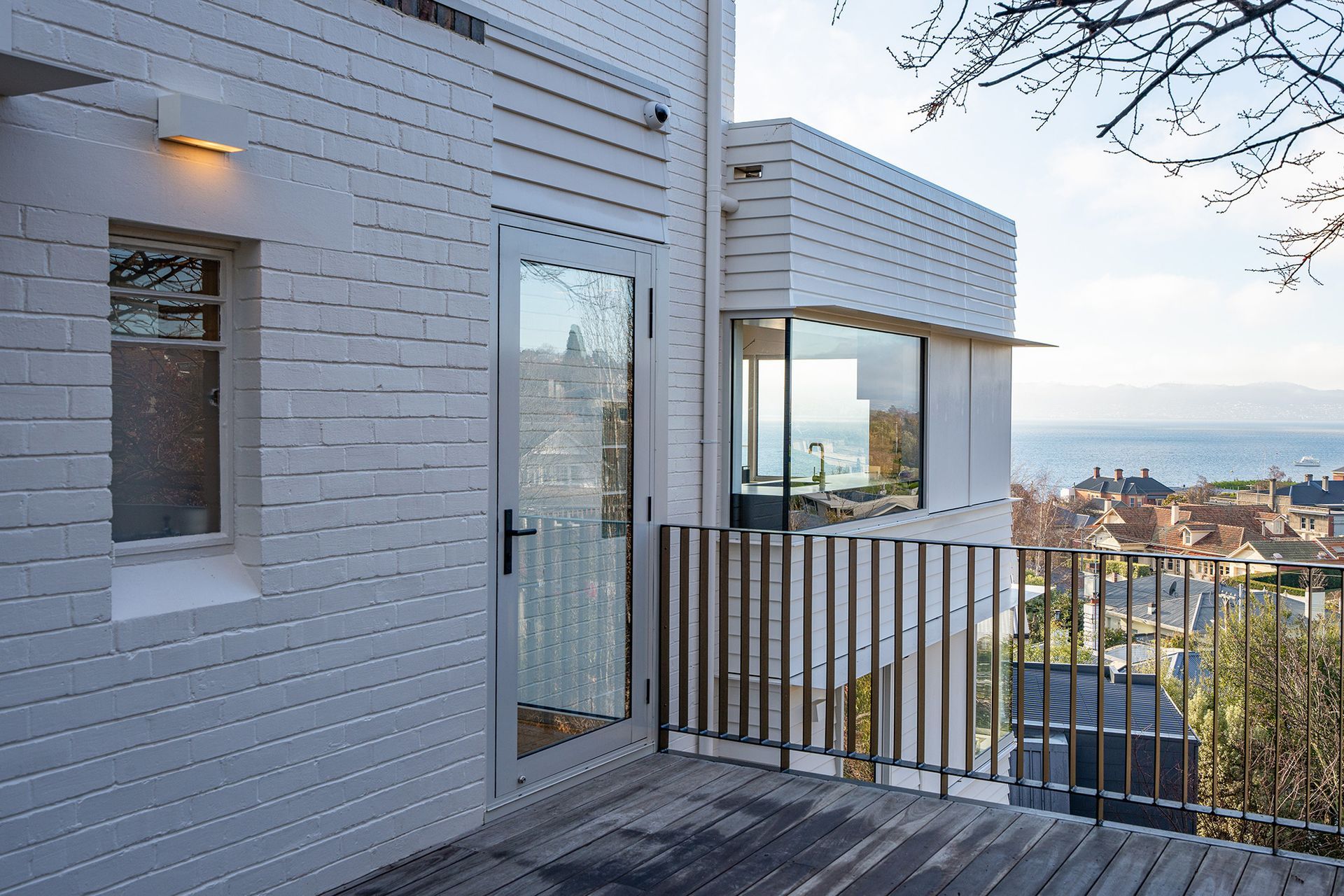 A white brick building with a balcony overlooking the ocean.