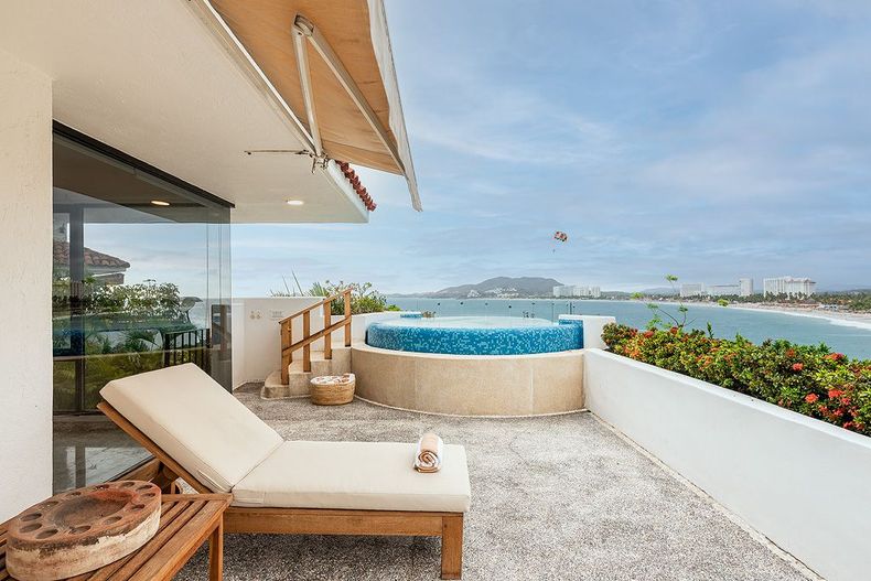 Lujosa terraza frente al mar con tumbona, jacuzzi y vista al océano.