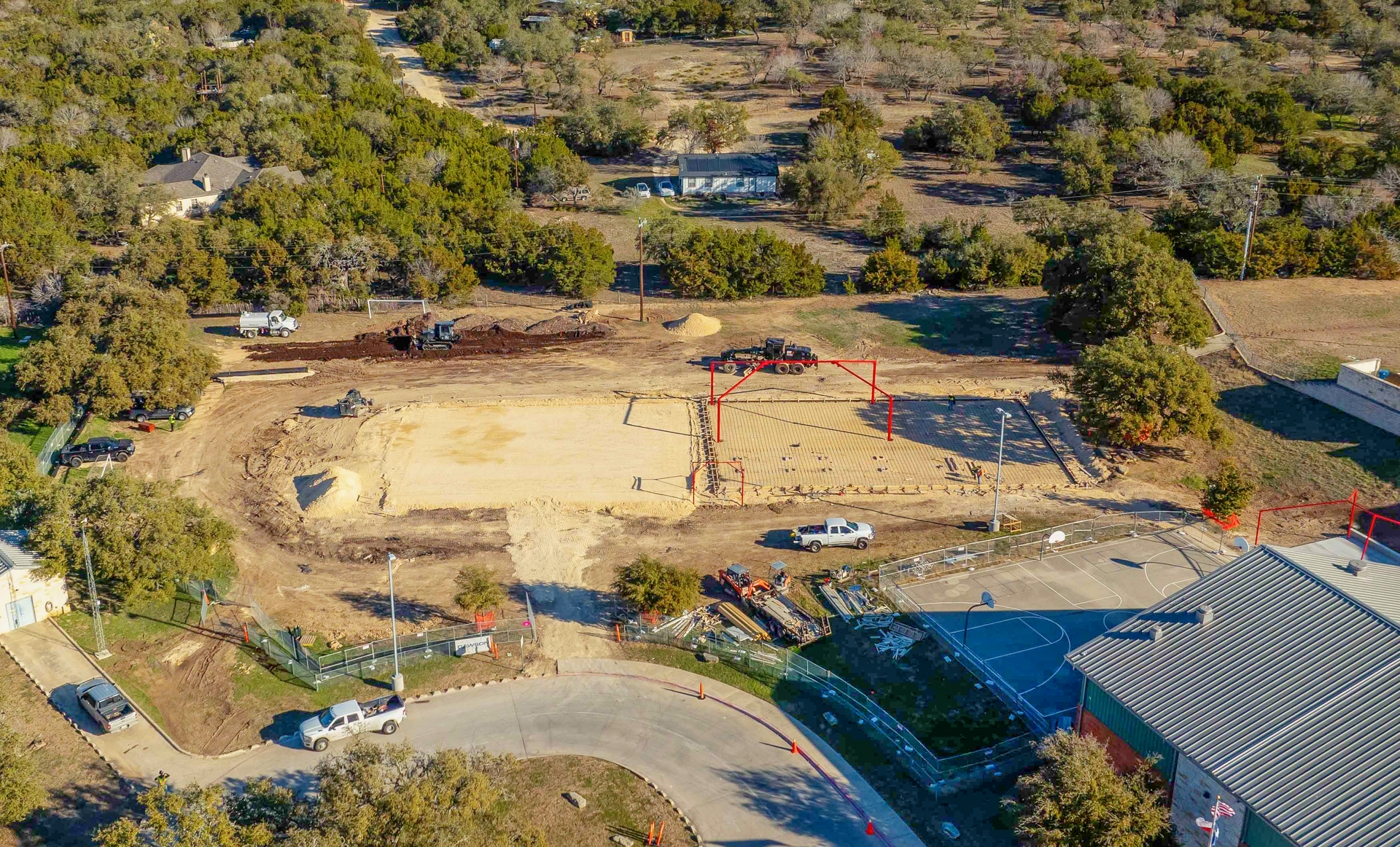 An aerial view of a construction site with a lot of trees in the background.