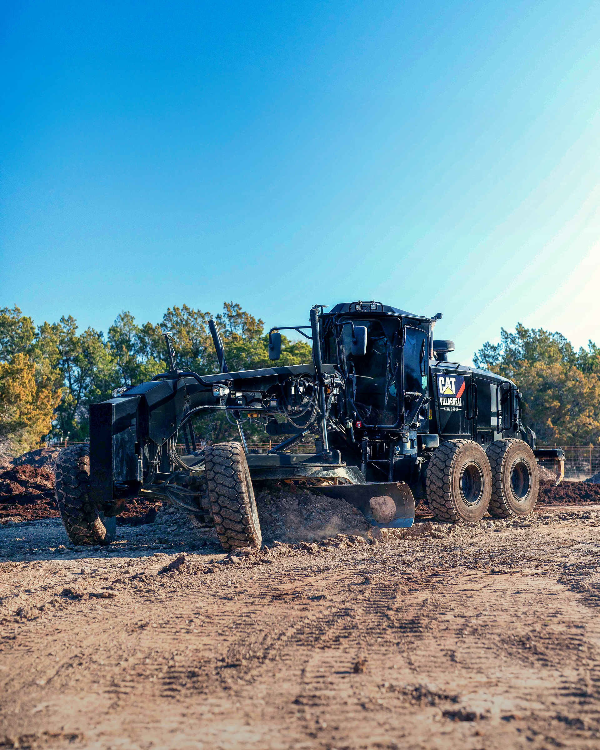 A black tractor is driving through a dirt field.