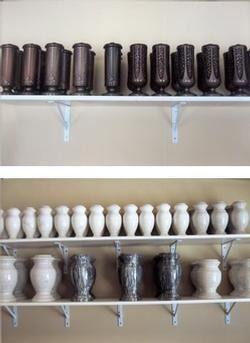 Shelves of assorted ceramic vases, dark and white, displayed in rows on a wall.