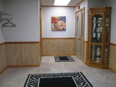 Empty hallway with beige carpet, wood paneling, a wall painting, and a glass display cabinet.
