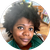 A person with curly dark hair looks toward the camera with a soft smile, set against a blurred indoor background.