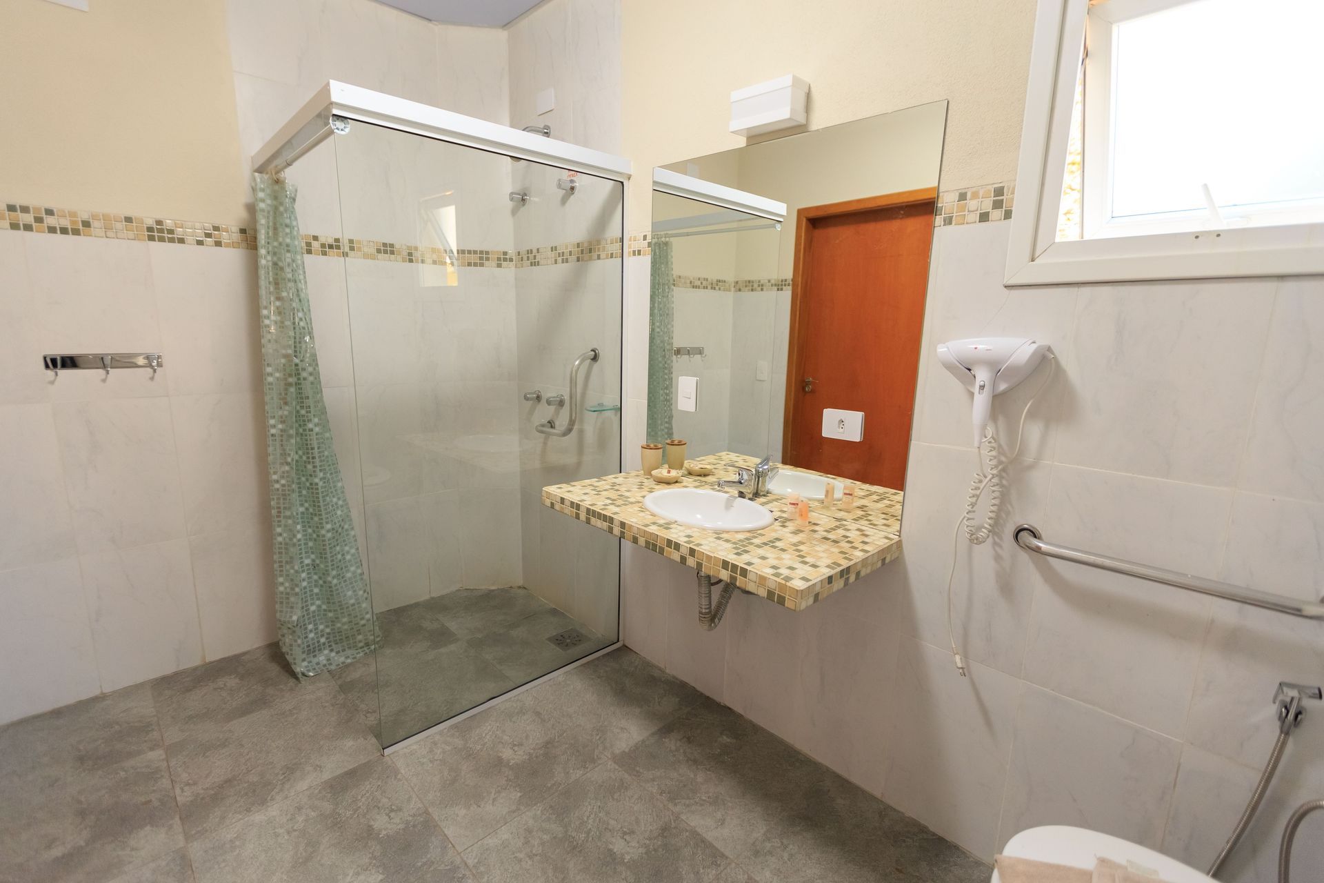 Walk-in bathtub with grab bar and faucet beside a tiled bathroom wall and window