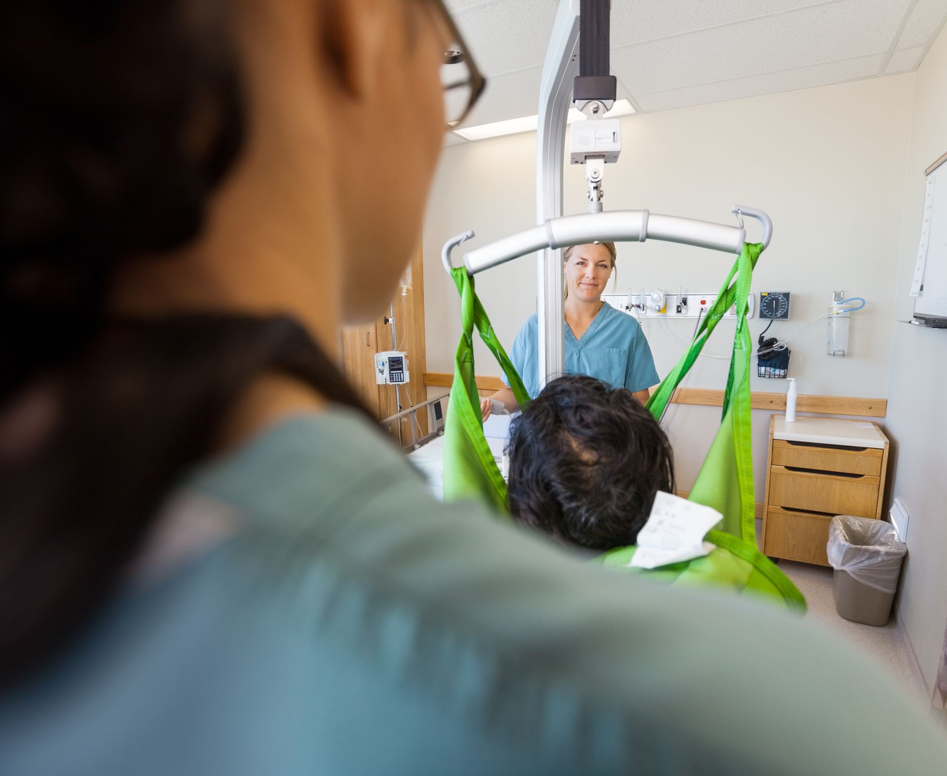 Patient being transferred on a hospital lift while a clinician assists nearby