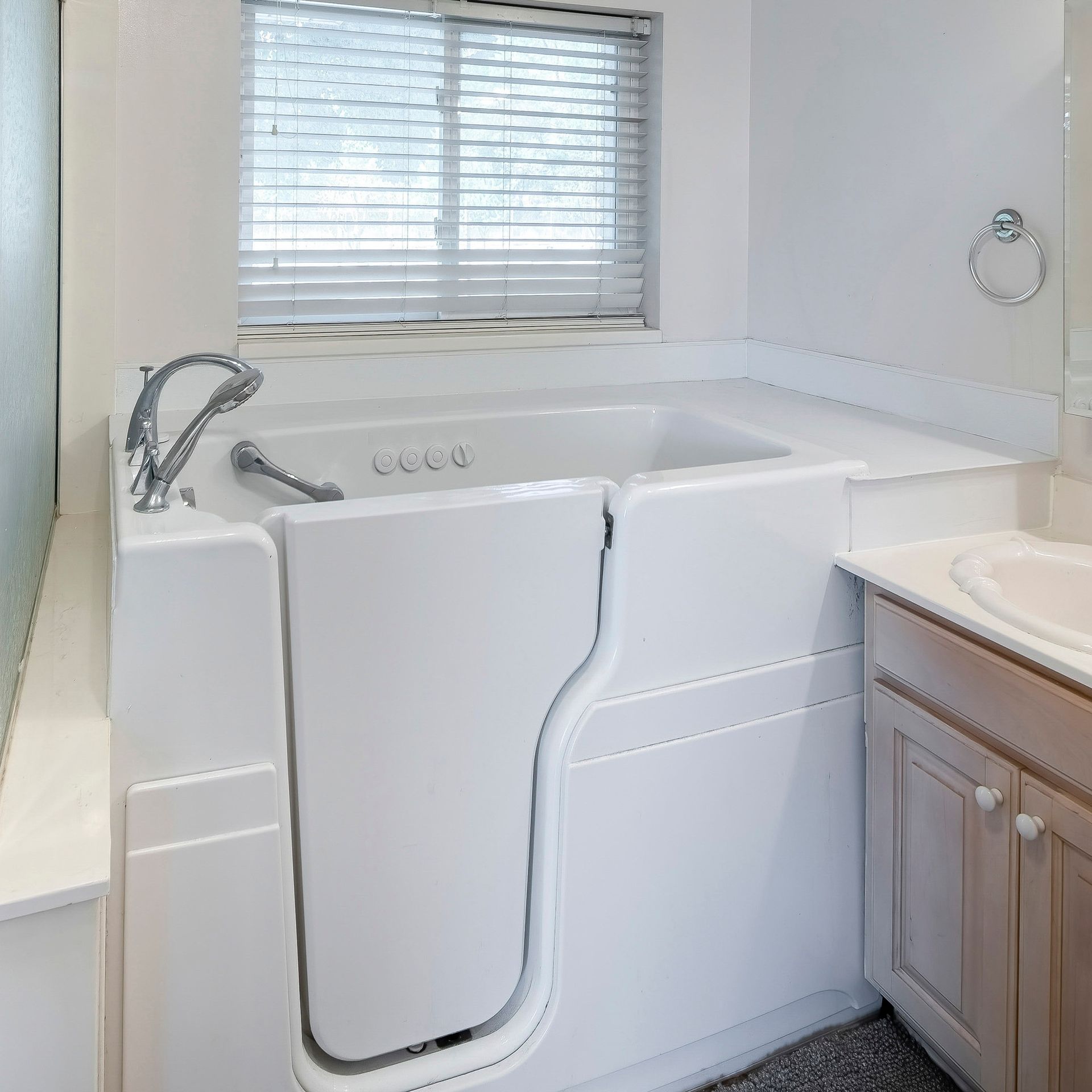 Silver stair lift beside beige carpeted stairs and a white door in a home entryway.