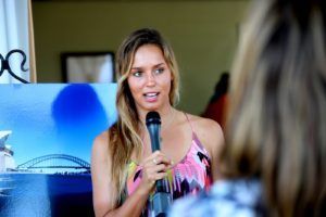 A woman is holding a microphone in front of a picture of a bridge.