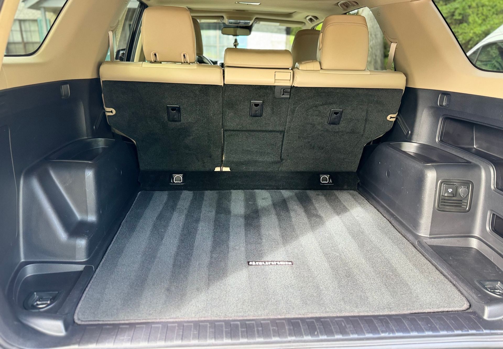 The trunk of a toyota 4runner is empty and has a carpeted floor.