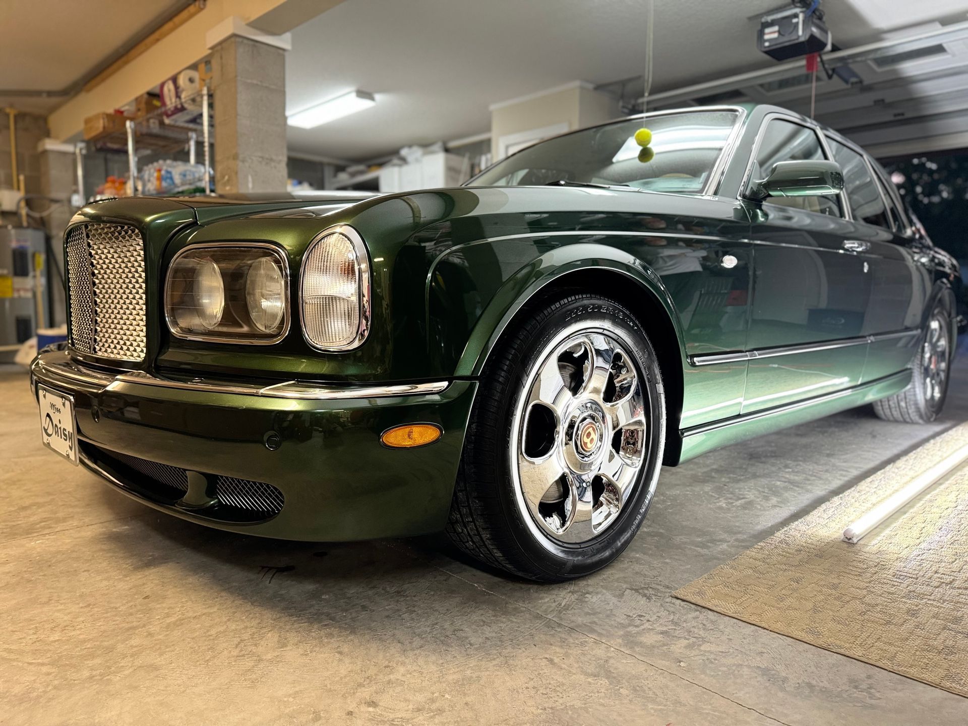 A green bentley is parked in a garage.
