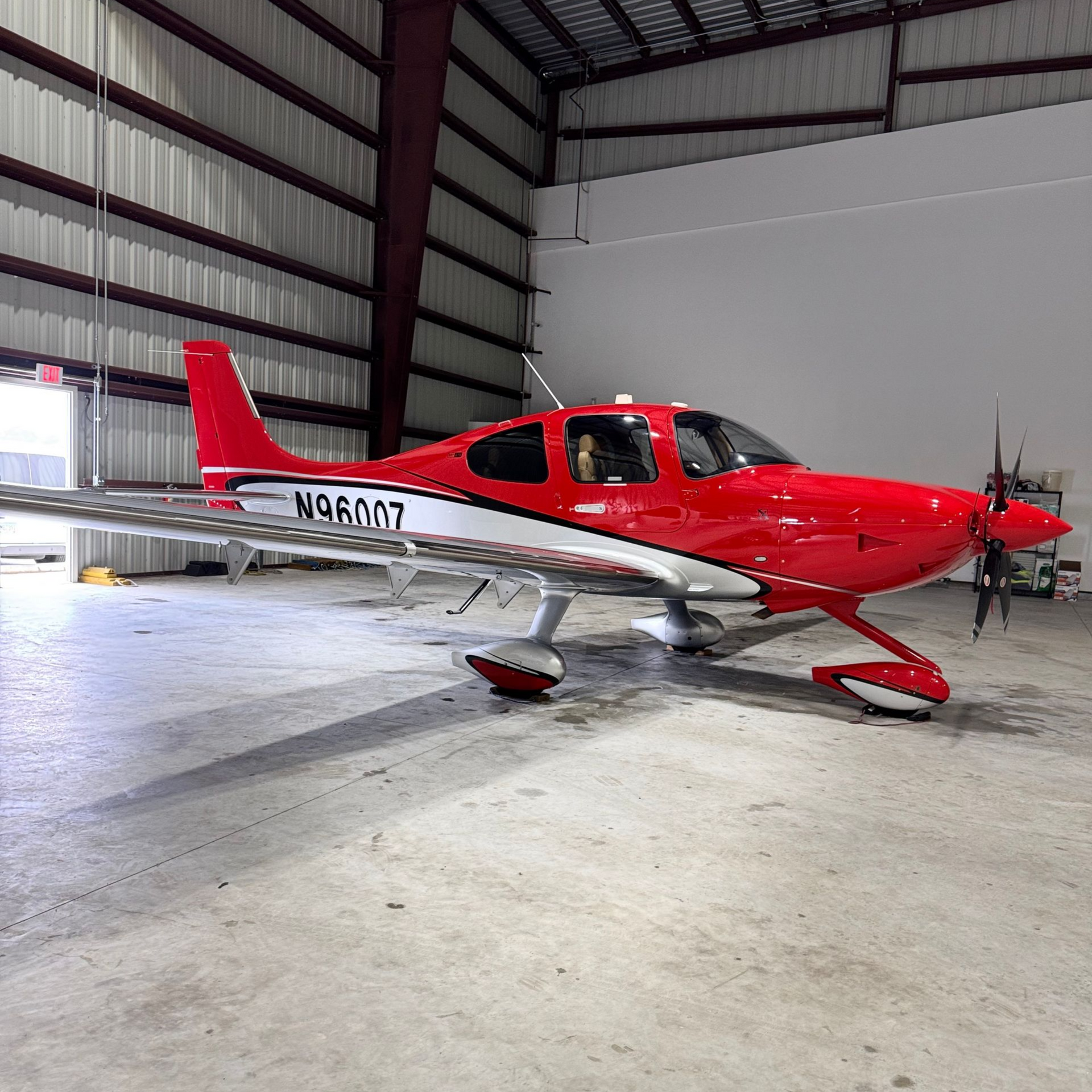 Red and white single-engine airplane parked inside a hangar, with registration N490MT visible.