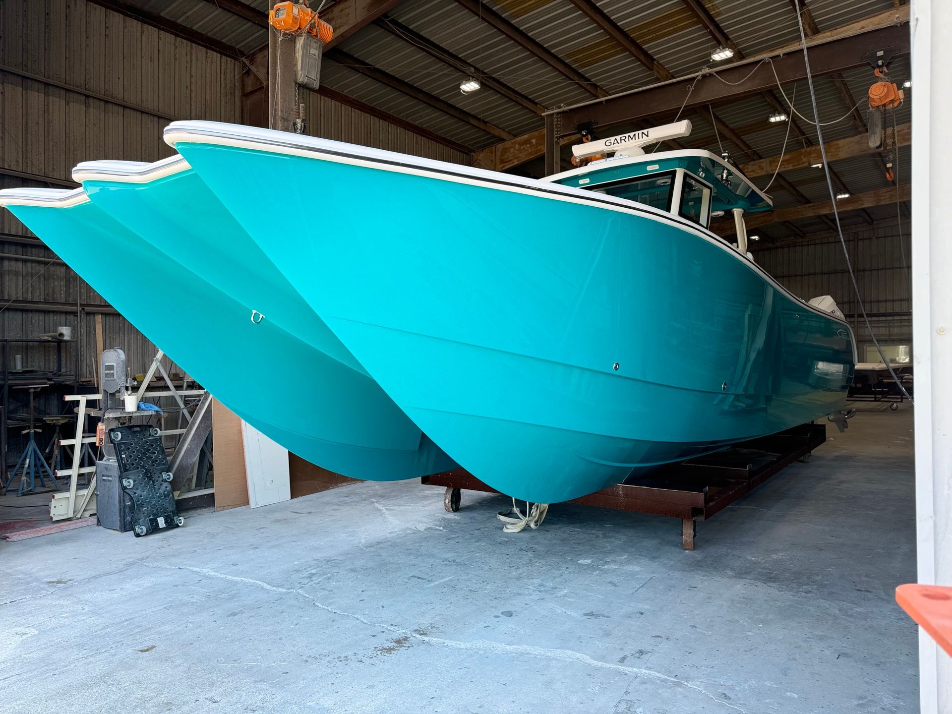 A large blue boat is sitting in a warehouse.
