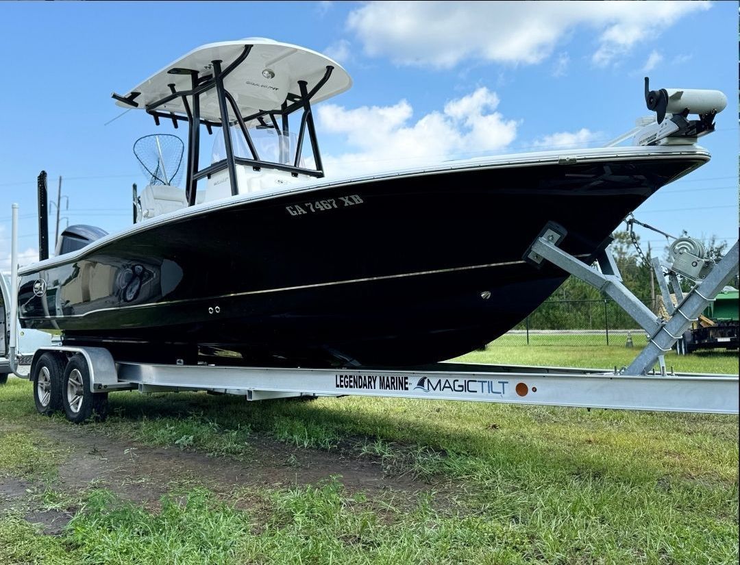 A boat is parked on a trailer in a grassy field.