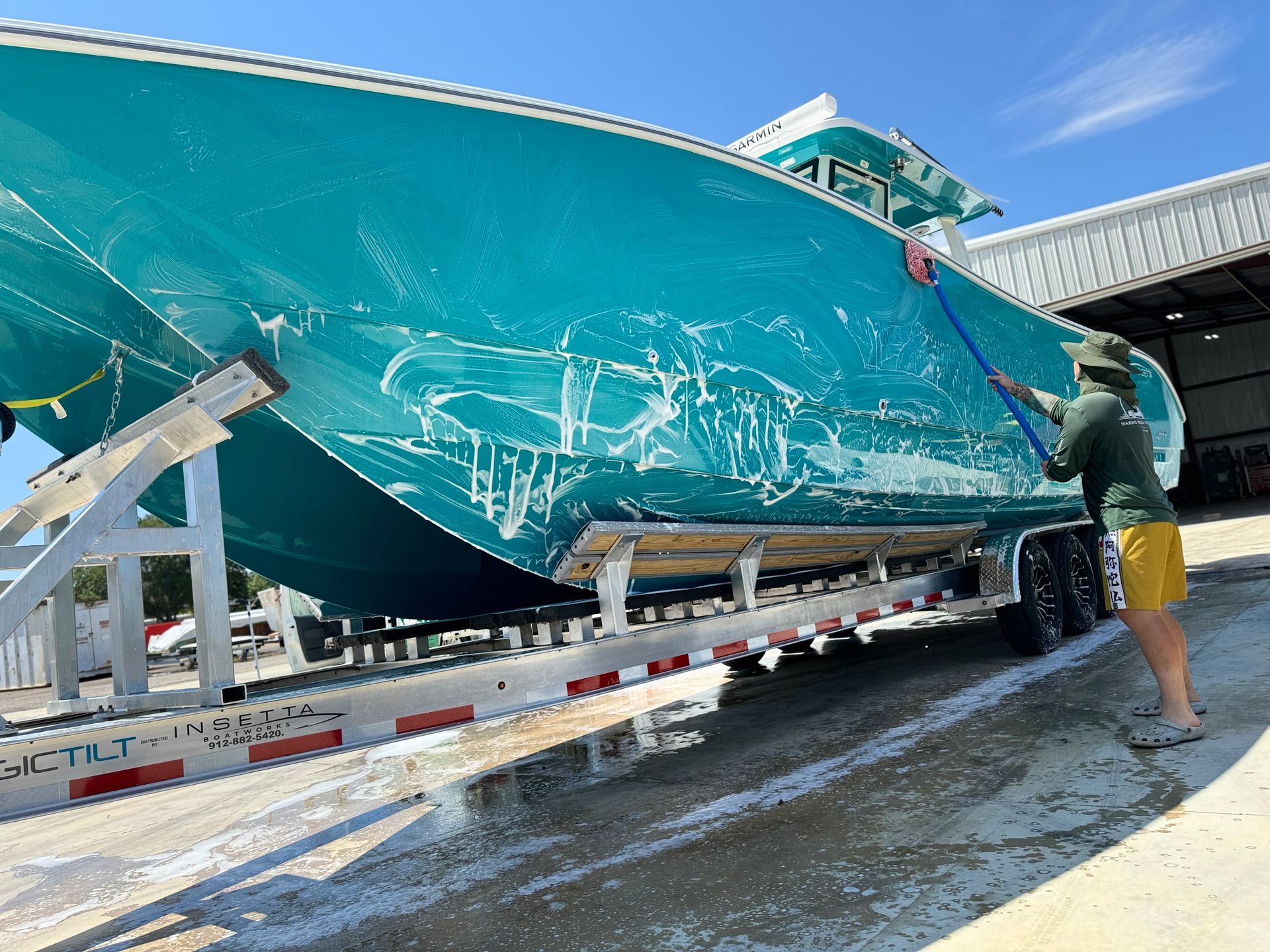 A man is washing a boat on a trailer.
