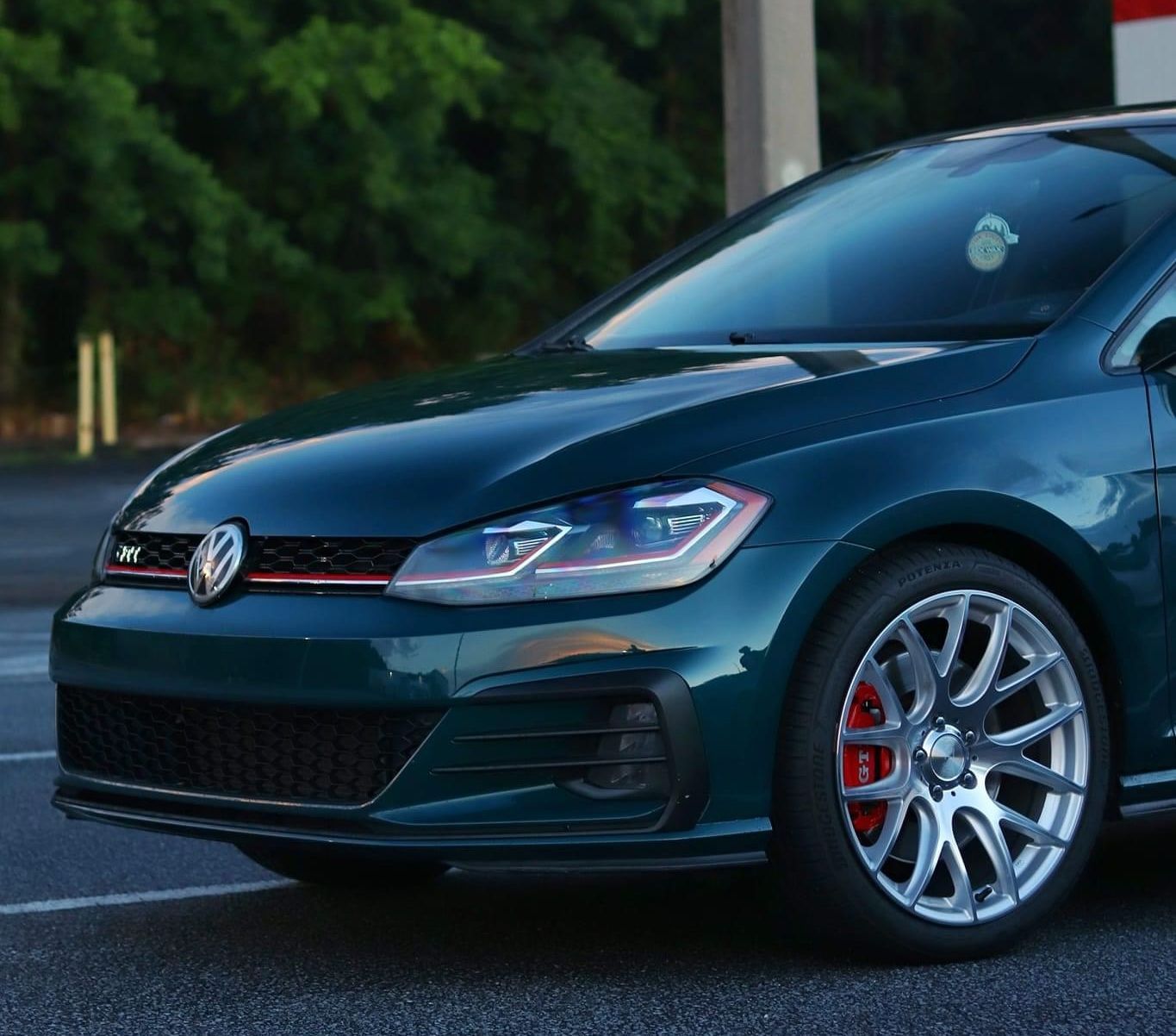 A green volkswagen golf is parked in a parking lot