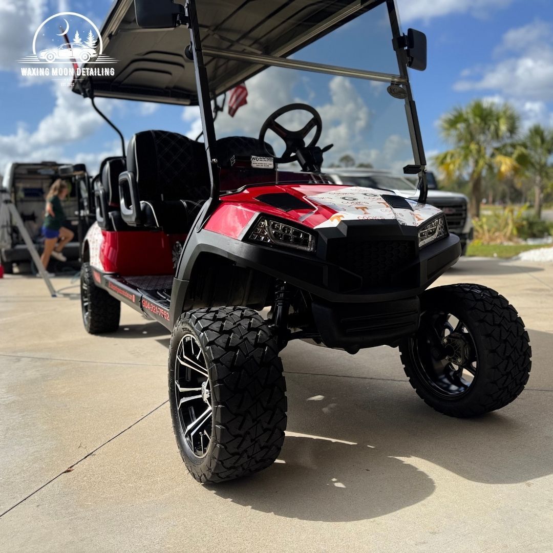A red and white golf cart is parked in a parking lot