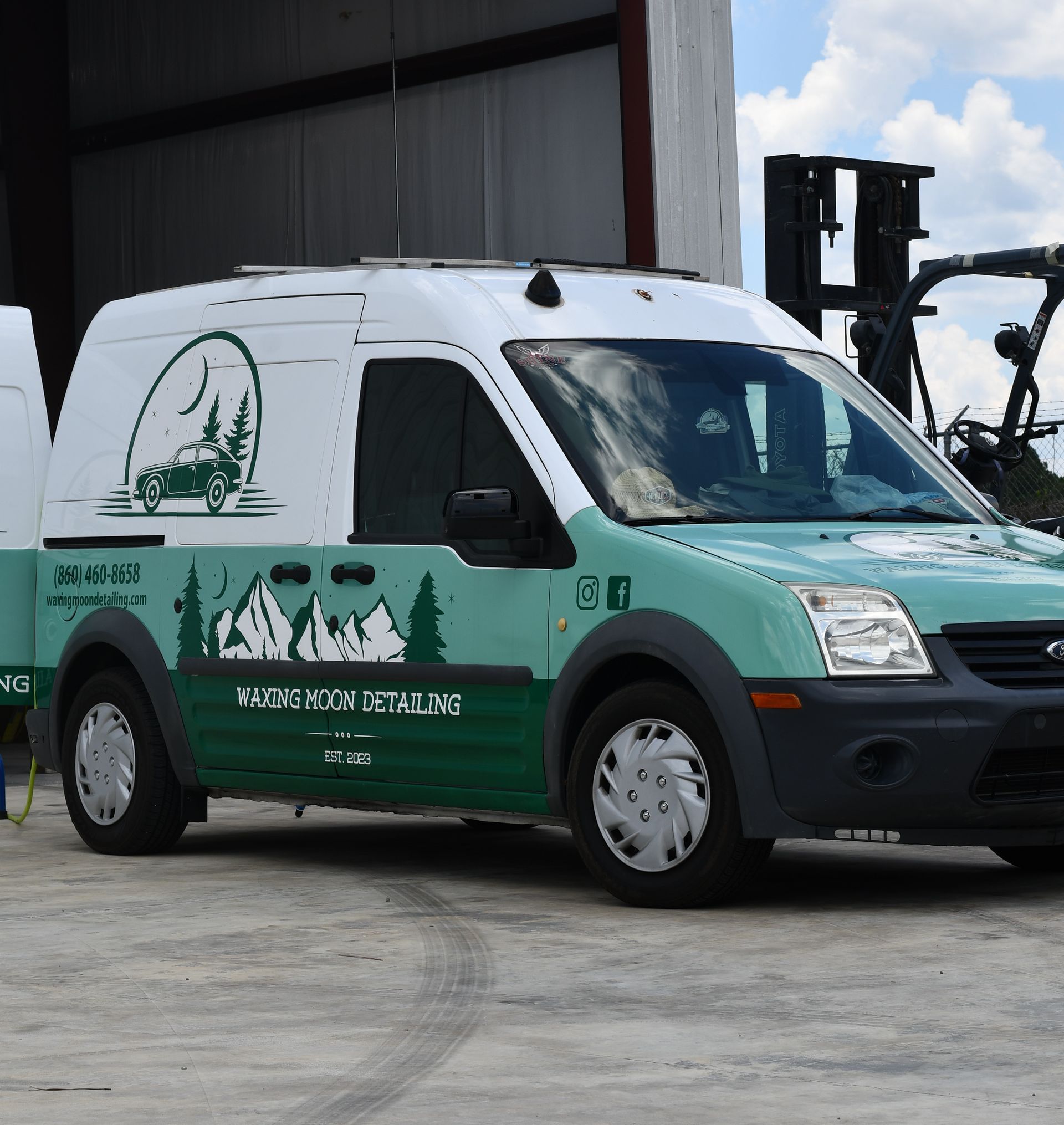 A green and white van is parked in front of a building