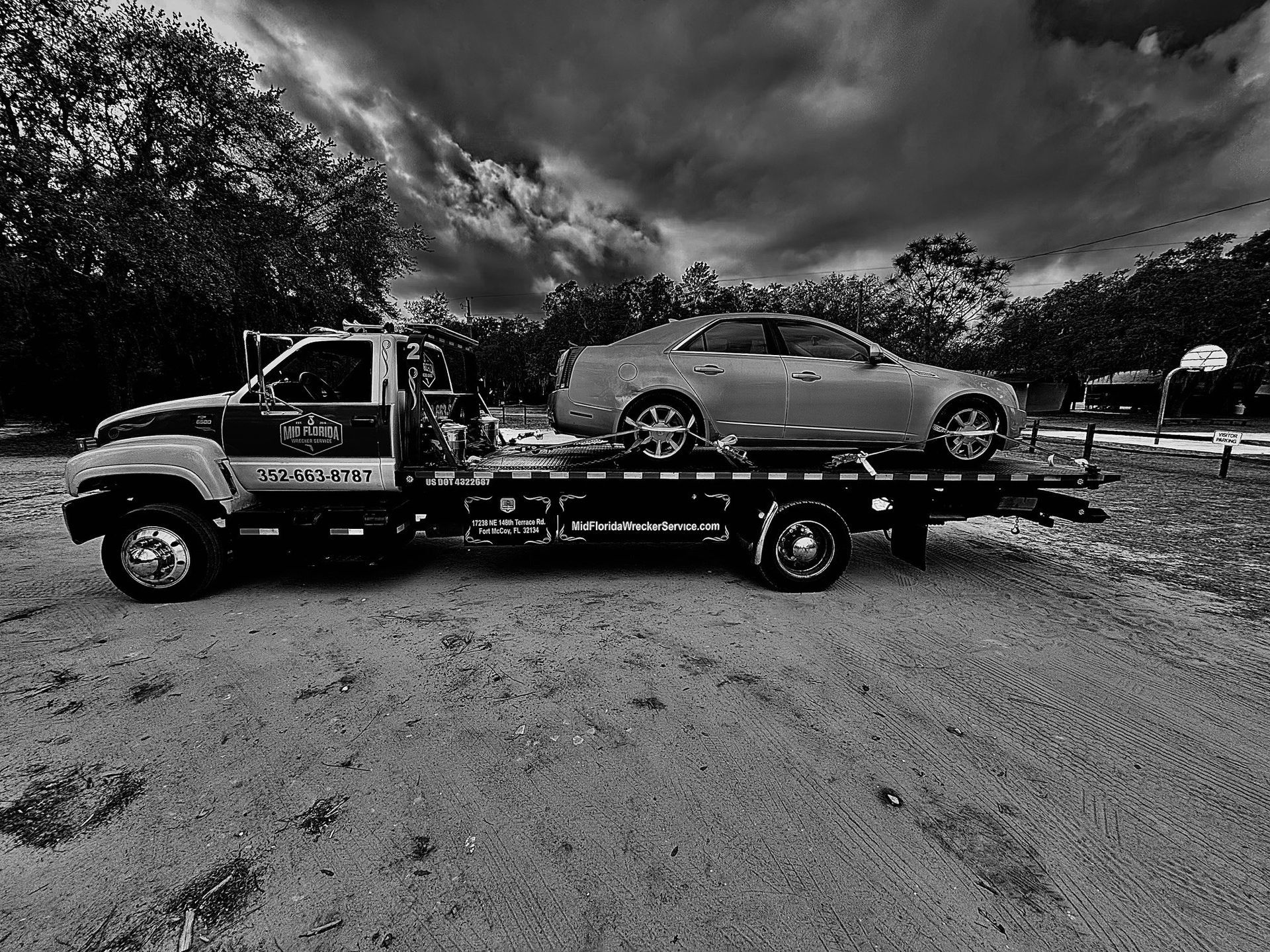Tow truck with a car loaded on its flatbed, outdoors.