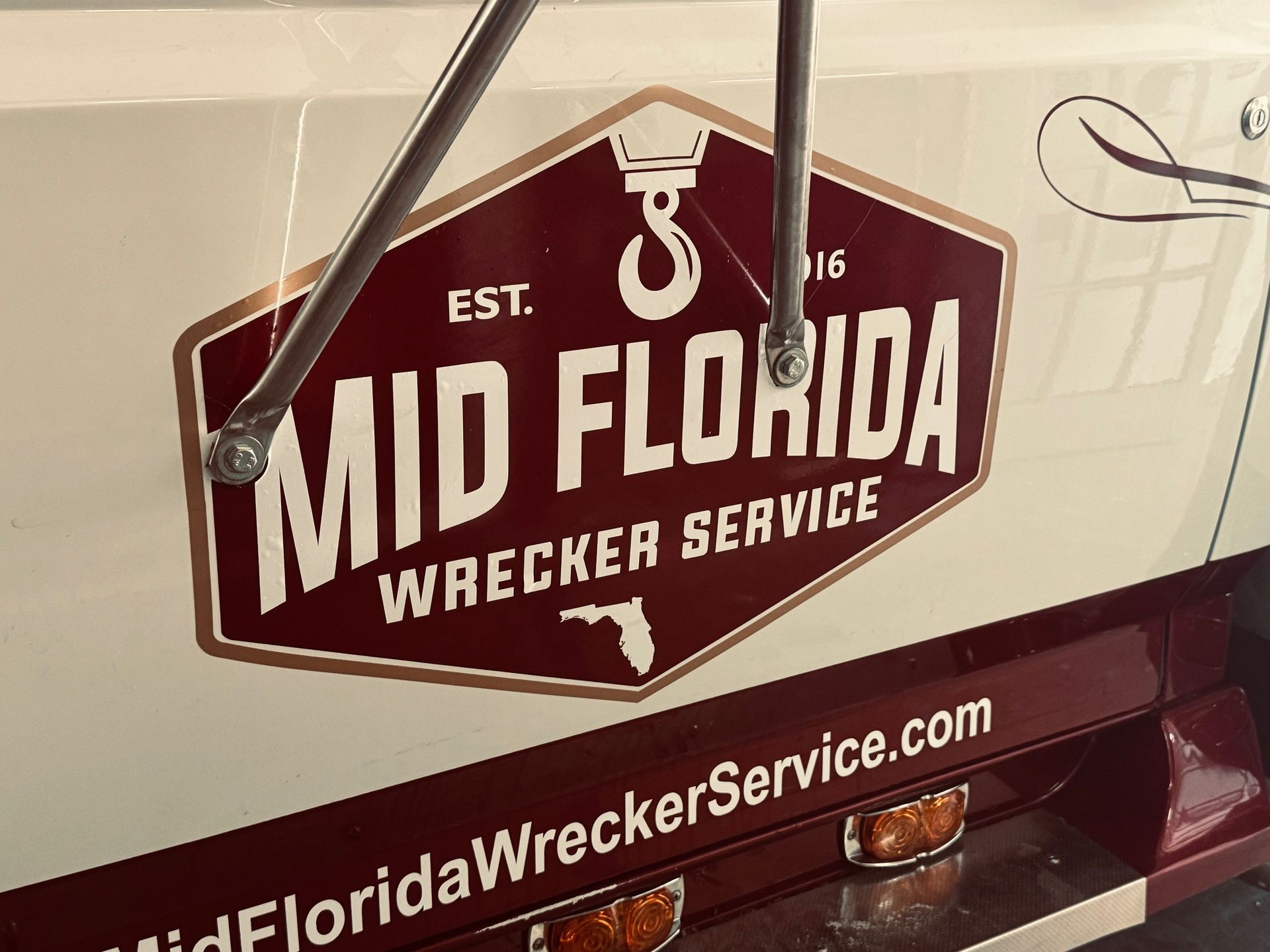 Mid Florida Wrecker Service logo on truck. Maroon, cream, and tan colors. Website address: MidFloridaWreckerService.com.