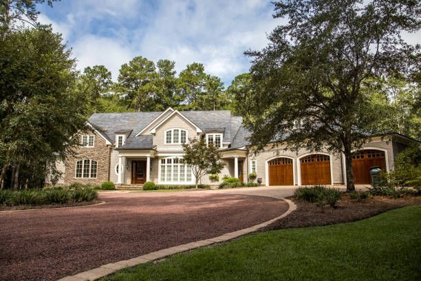 A large house with a driveway leading to it is surrounded by trees.