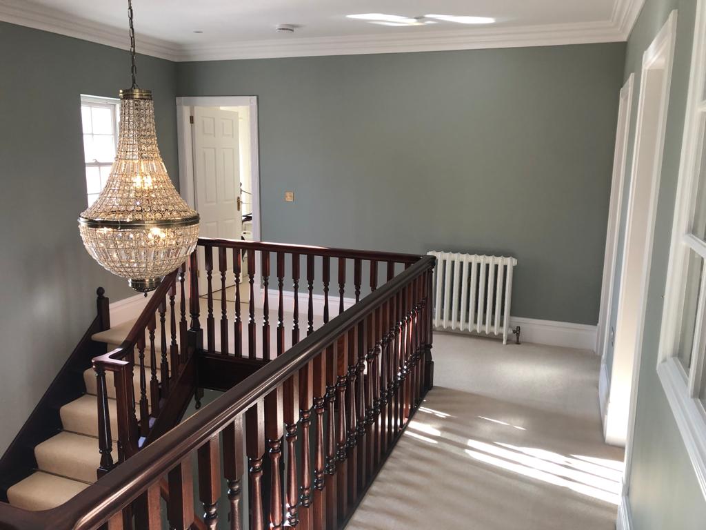 This is a photo of a landing with a wooden painted baluster rail and grey painted walls