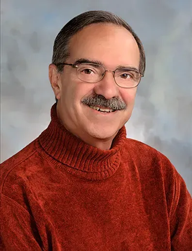 A man with glasses and a mustache is wearing a red sweater.
