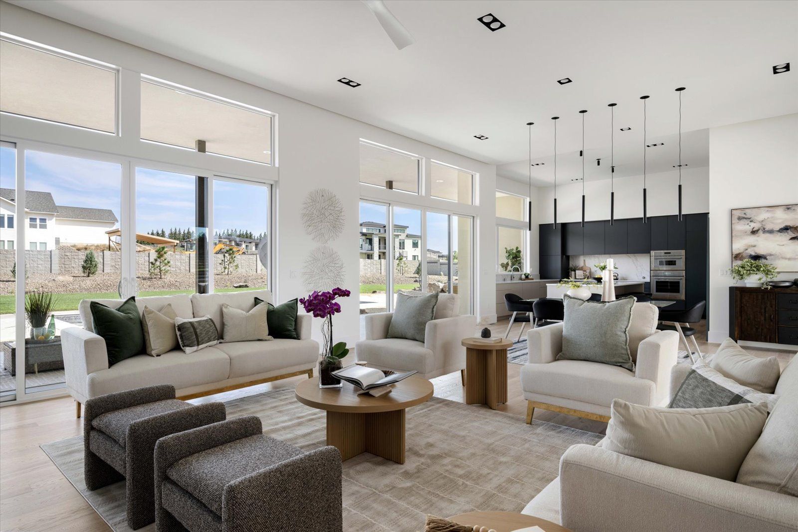 Spacious, modern living room with neutral colors, large windows, and a view of the outside.