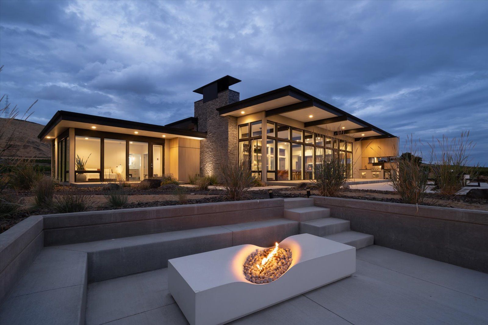 A modern house with two garages and a driveway at sunset.