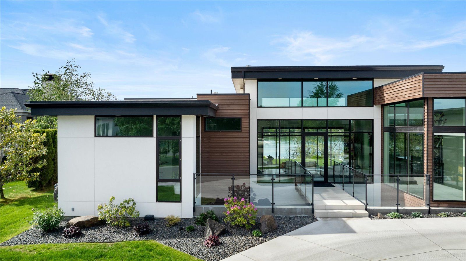 A modern house with a lot of windows and a large driveway.