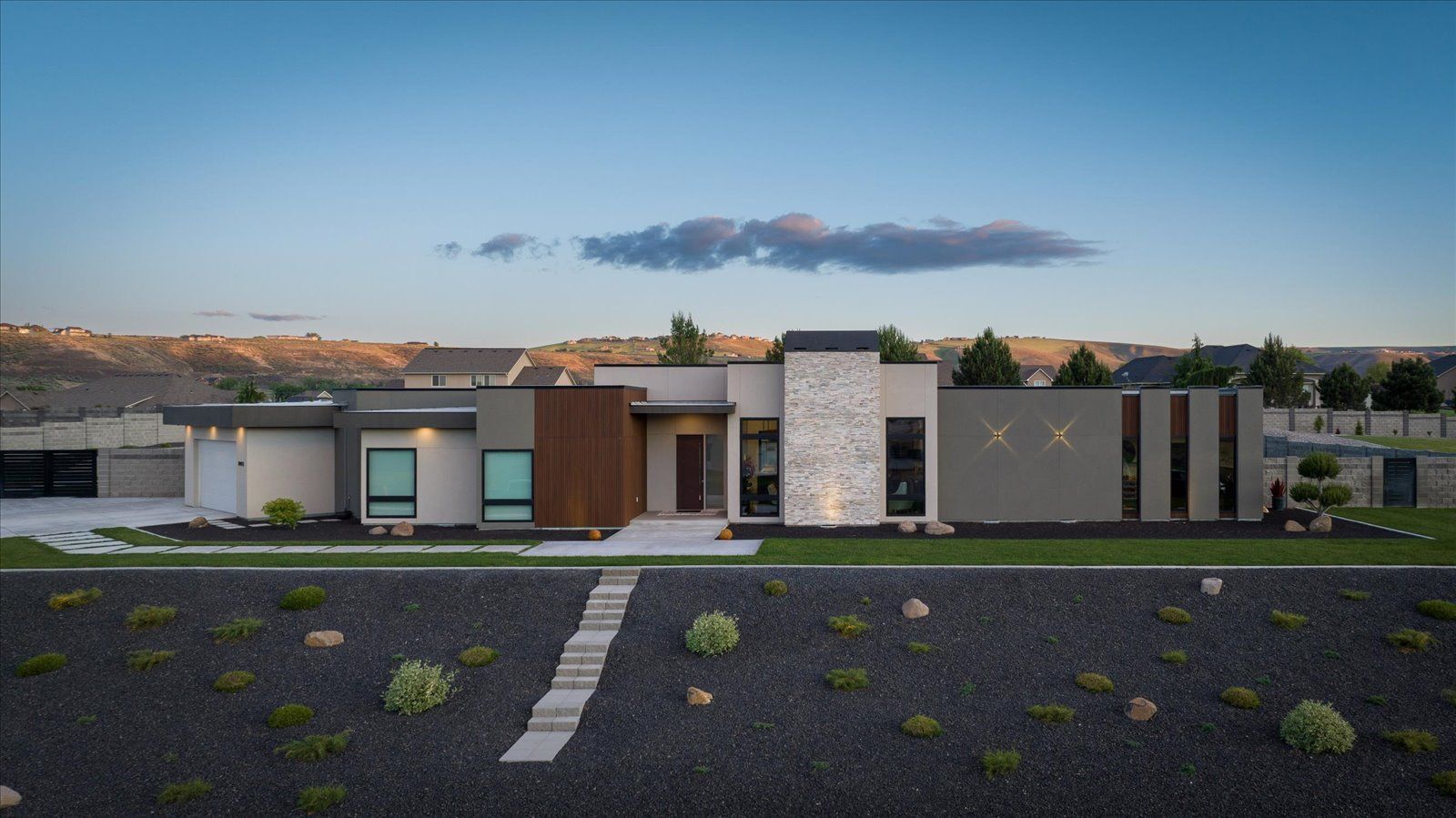 A modern house is sitting on top of a lush green hillside.