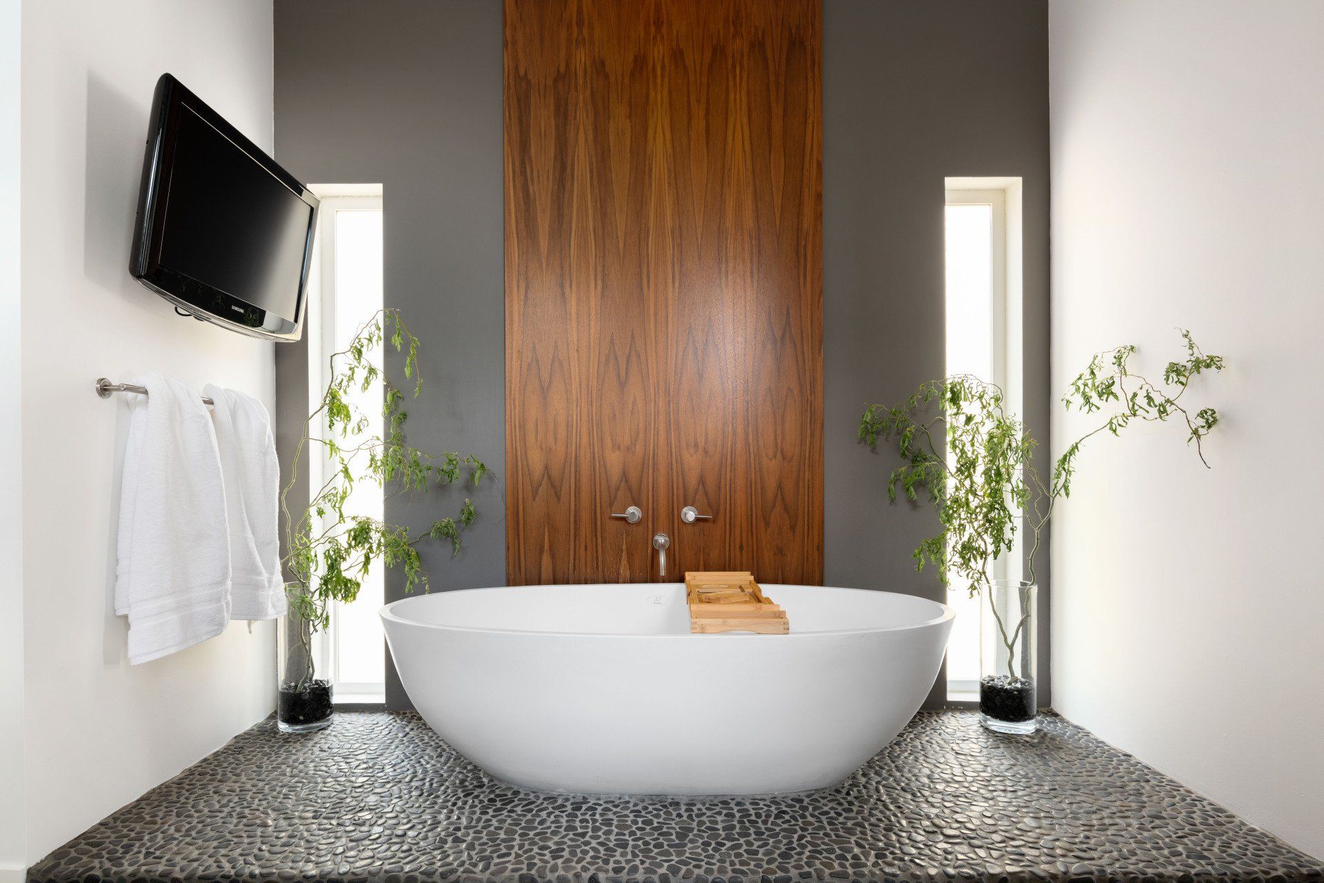 A bathroom with a bathtub and a television on the wall.