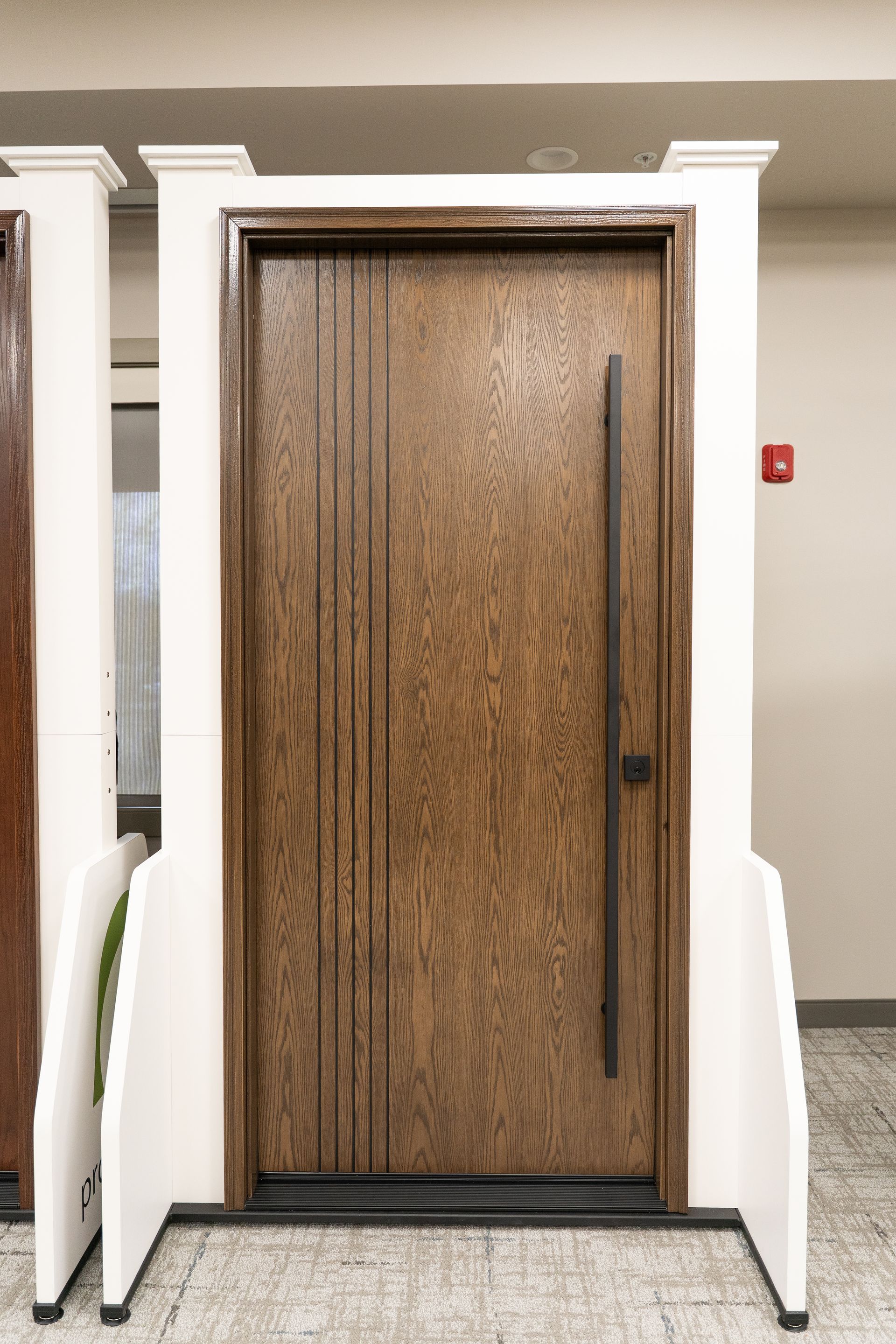 Wooden office door with dark metal handle framed by white columns in a hallway.